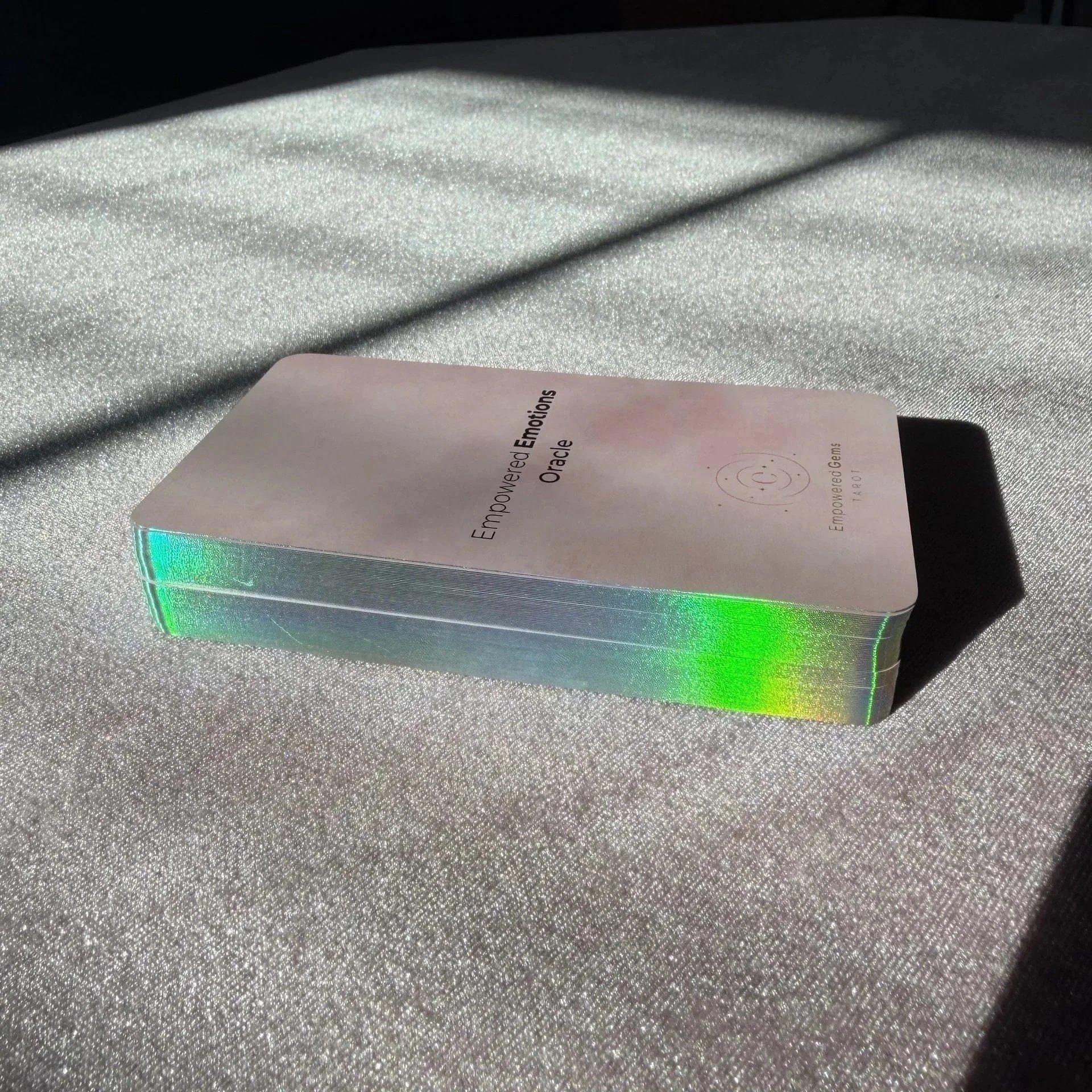 Empowered Emotions Oracle holographic gilt edge card deck in sunlight.
