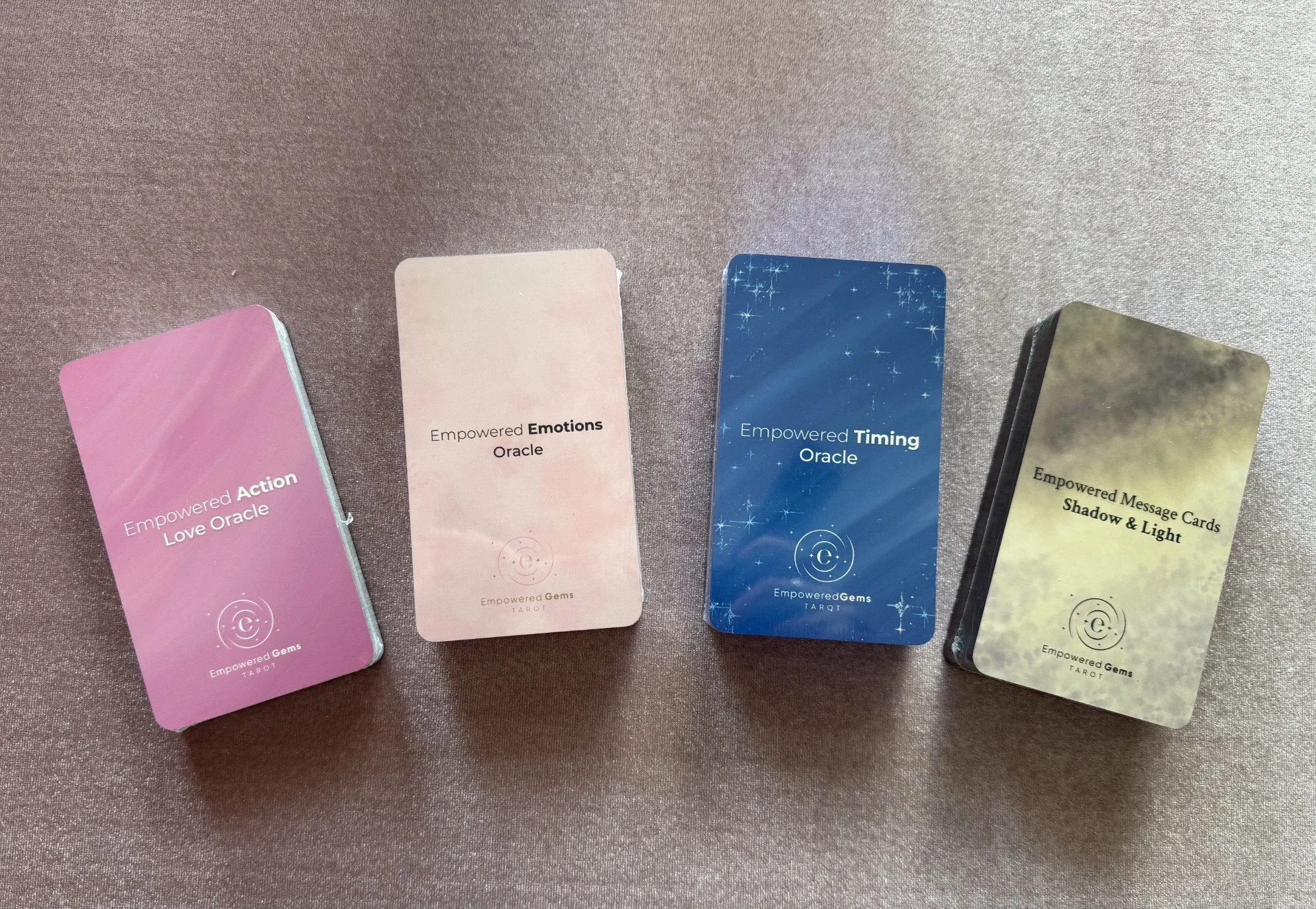 The four Empowered Gems Tarot oracle decks displayed together: Empowered Emotions Oracle, Empowered Action Love Oracle, Empowered Timing Oracle, and Empowered Message Cards - Shadow & Light.