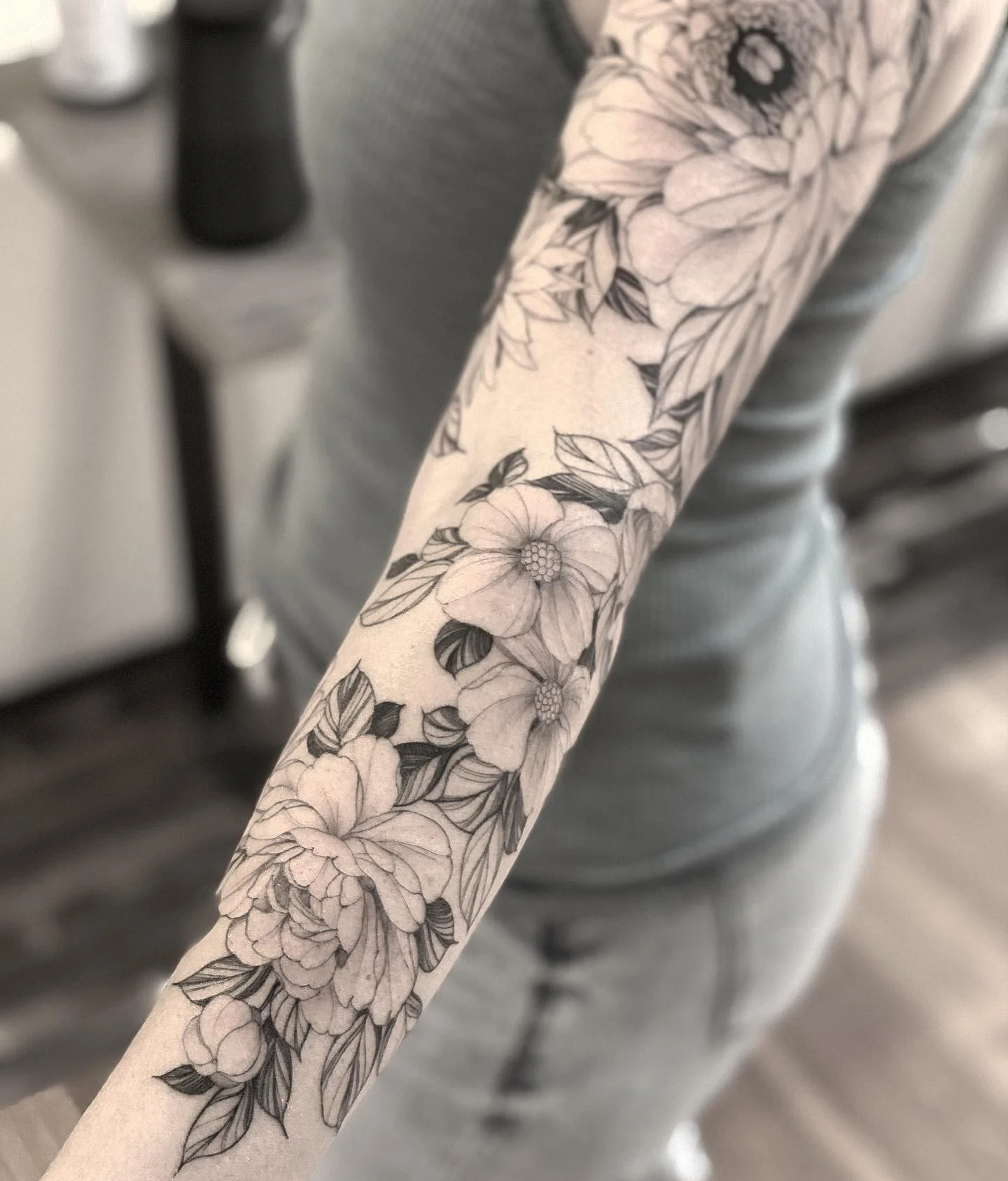 A person's arm with a floral tattoo design featuring blooming flowers and leaves.