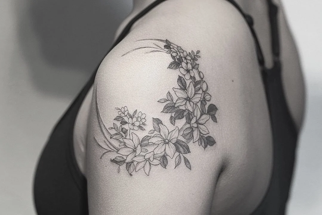 Black and gray floral tattoo on person's upper arm and shoulder