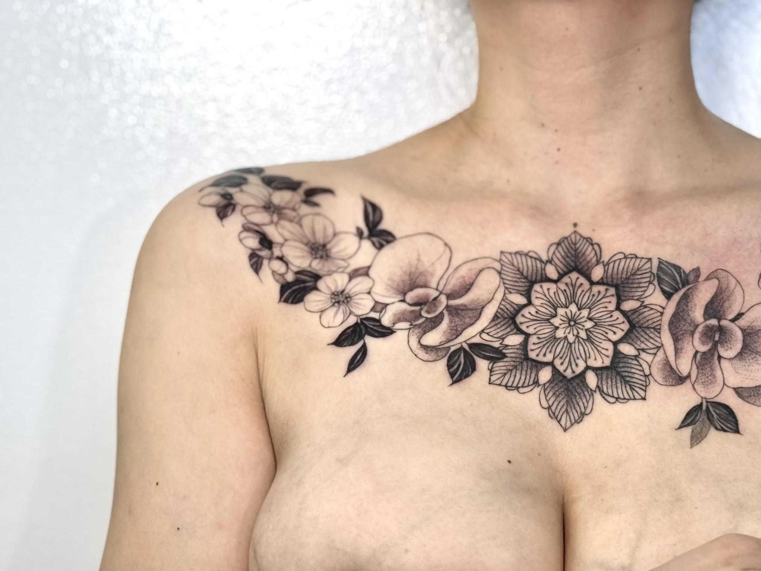 Black and gray floral tattoo across the person's chest and shoulder.