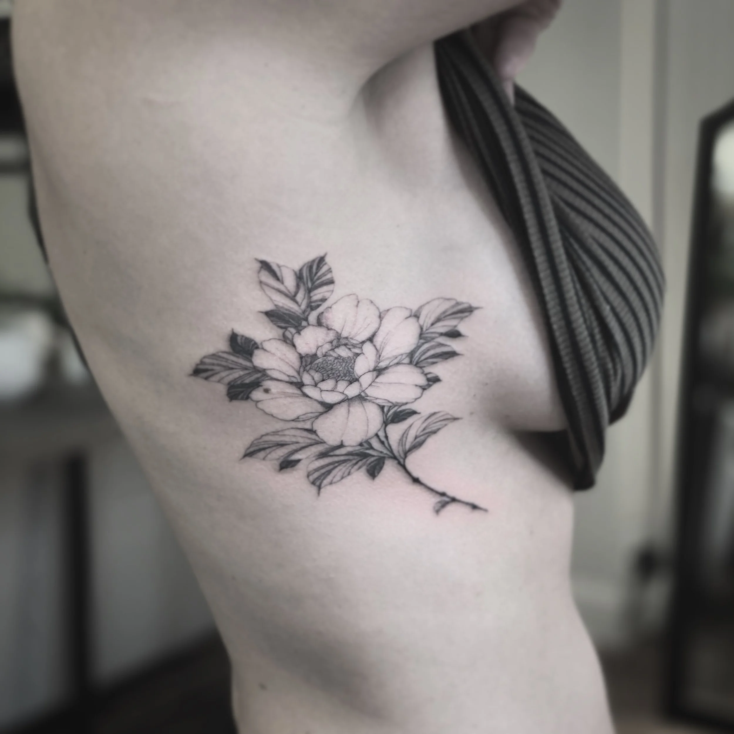 Best bay area fine line peony flower tattoo on the ribs