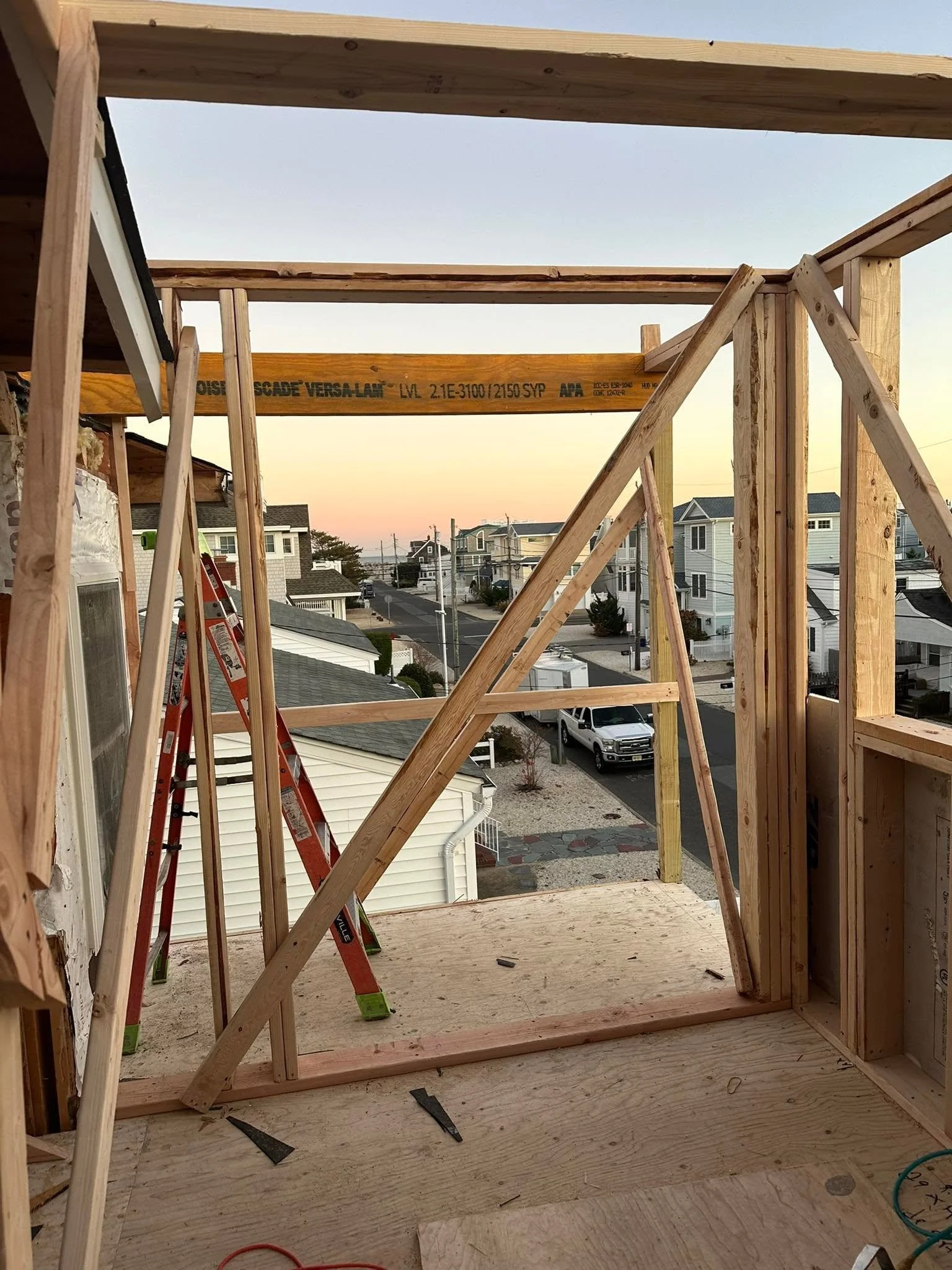 Wood framing on a building under construction, view from the inside looking out at a neighborhood and street.
