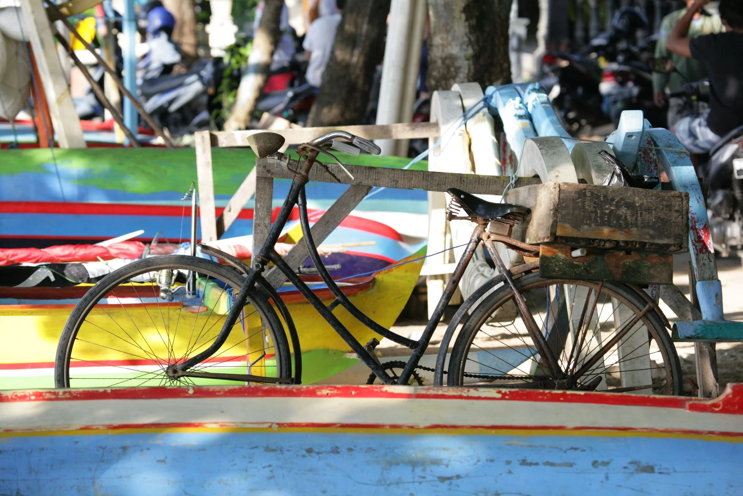 Old bicycle parked among colorful, painted wooden boats.