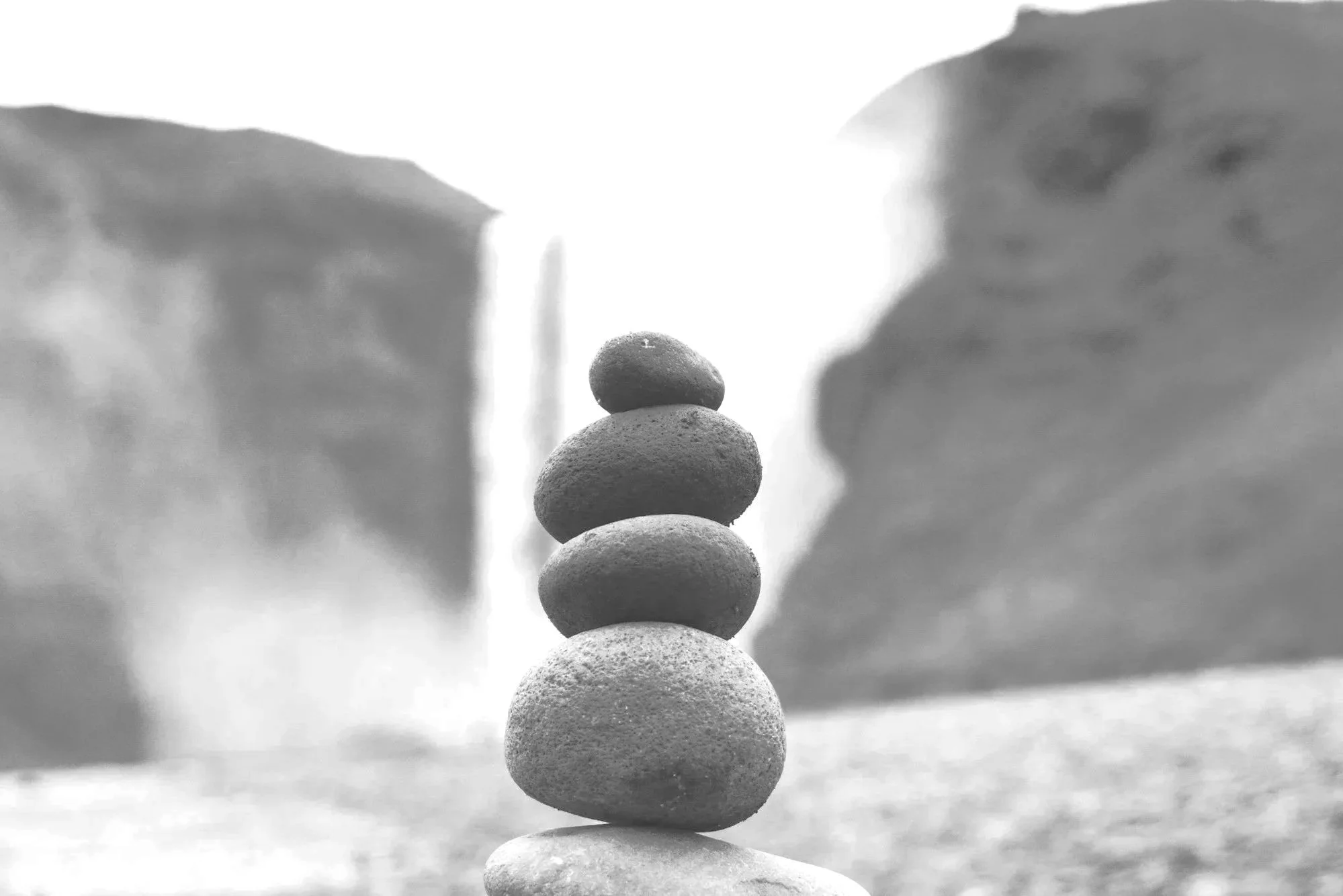 Stacked smooth stones balanced against a background of cliffs.