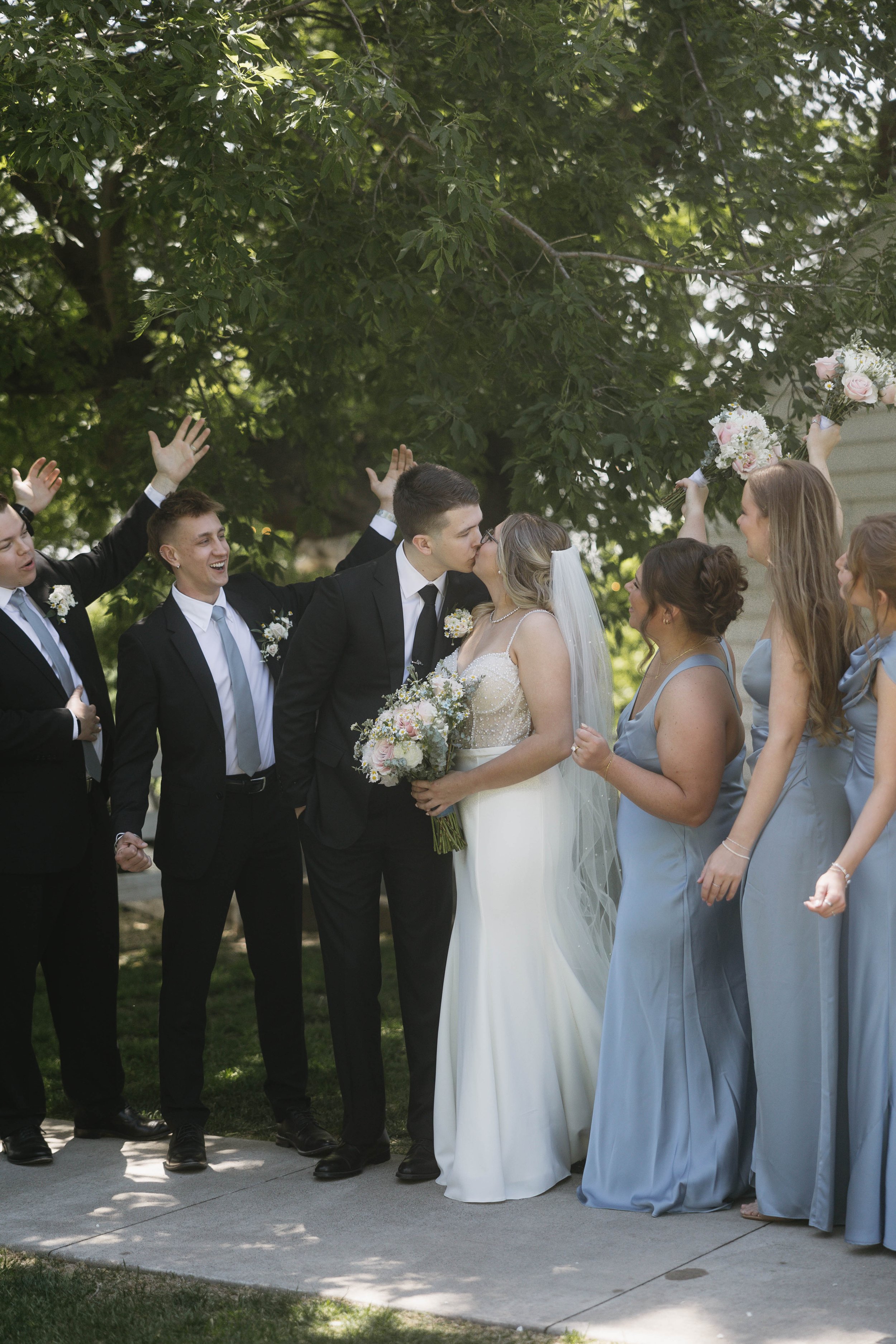 Bride and groom holding hands on a staircase, sharing a moment during their wedding. The bride is wearing a white strapless wedding gown, and the groom is wearing a dark suit with a white tie. They are standing by a wooden banister with a decorative, patterned carpet on the stairs.