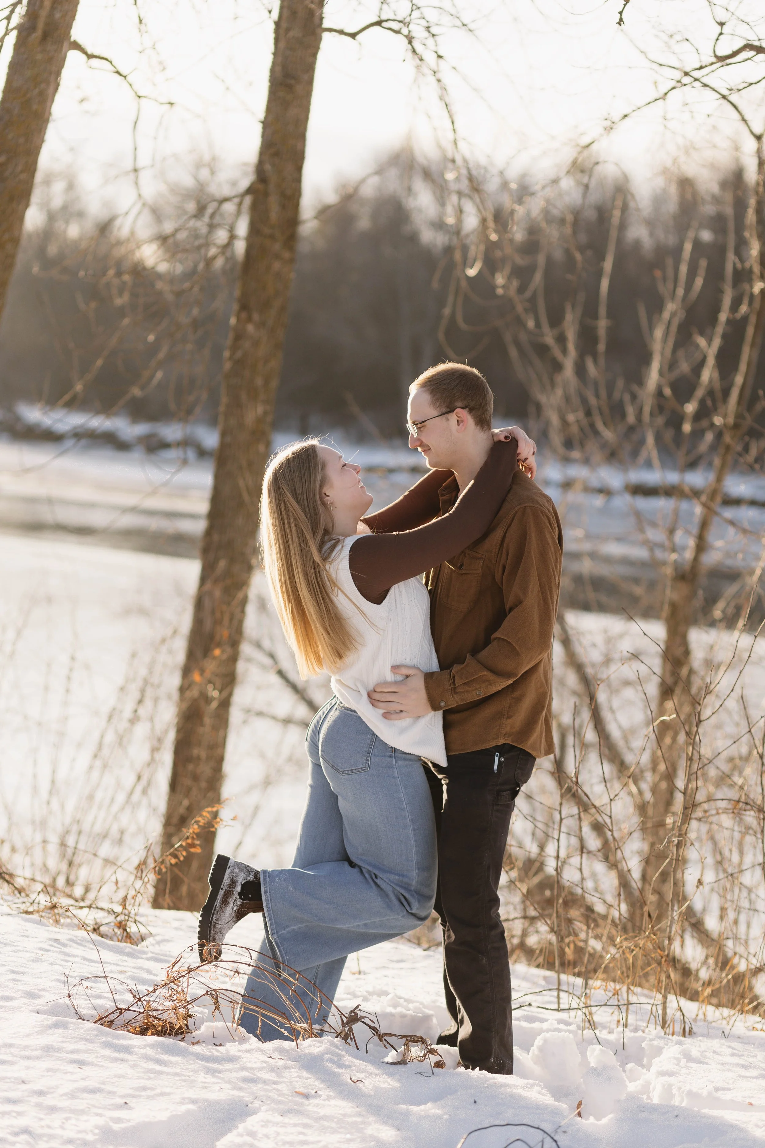 Engaged couple at their engagement session in northern Minnesota, playing in the snow, candid