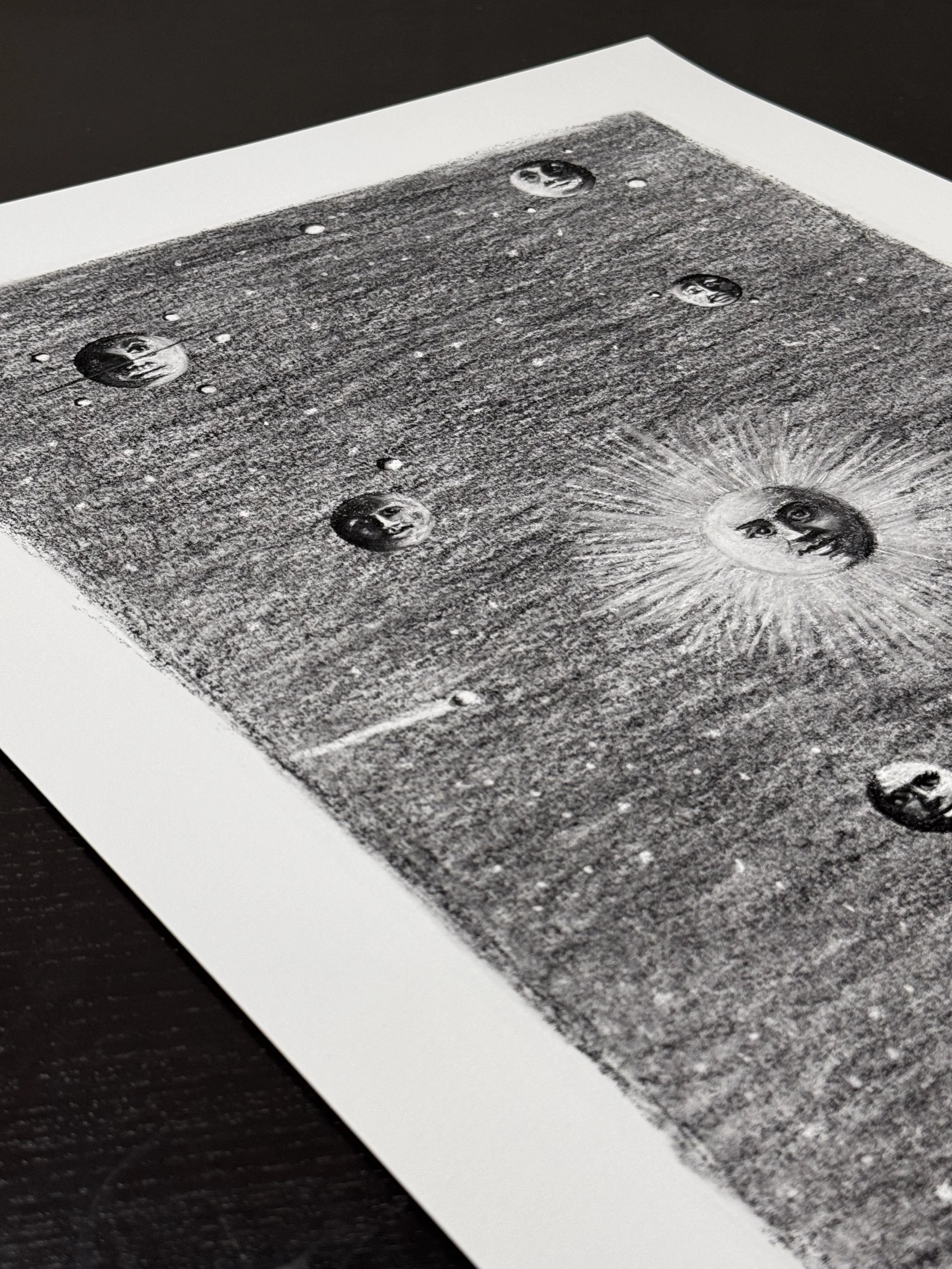 Angled view of the Celestial Reverie limited edition art print, showing detailed charcoal textures, celestial faces, and atmospheric space imagery on fine art paper.