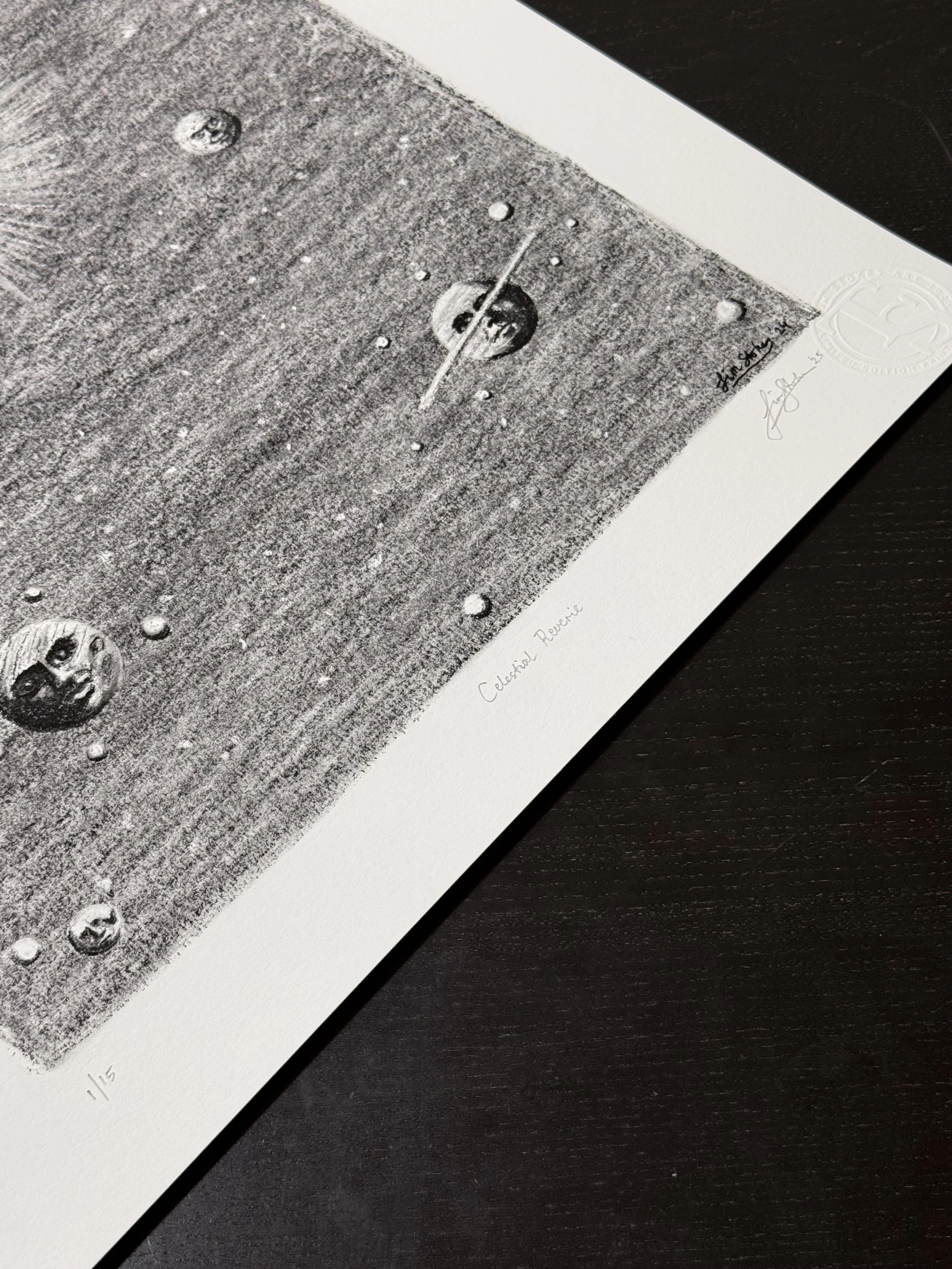 Close up angled view of the Celestial Reverie art print highlighting charcoal shading, moon faces, and hand signed details on textured fine art paper.
