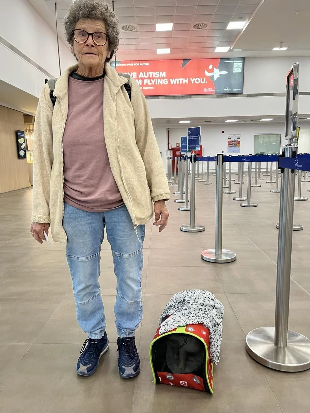 A Flight Partner waiting at the airport check-in with a cat carrier