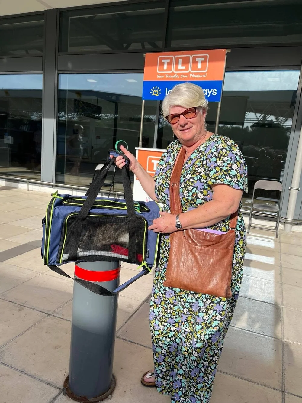 A happy traveller with a cat carrier at the airport