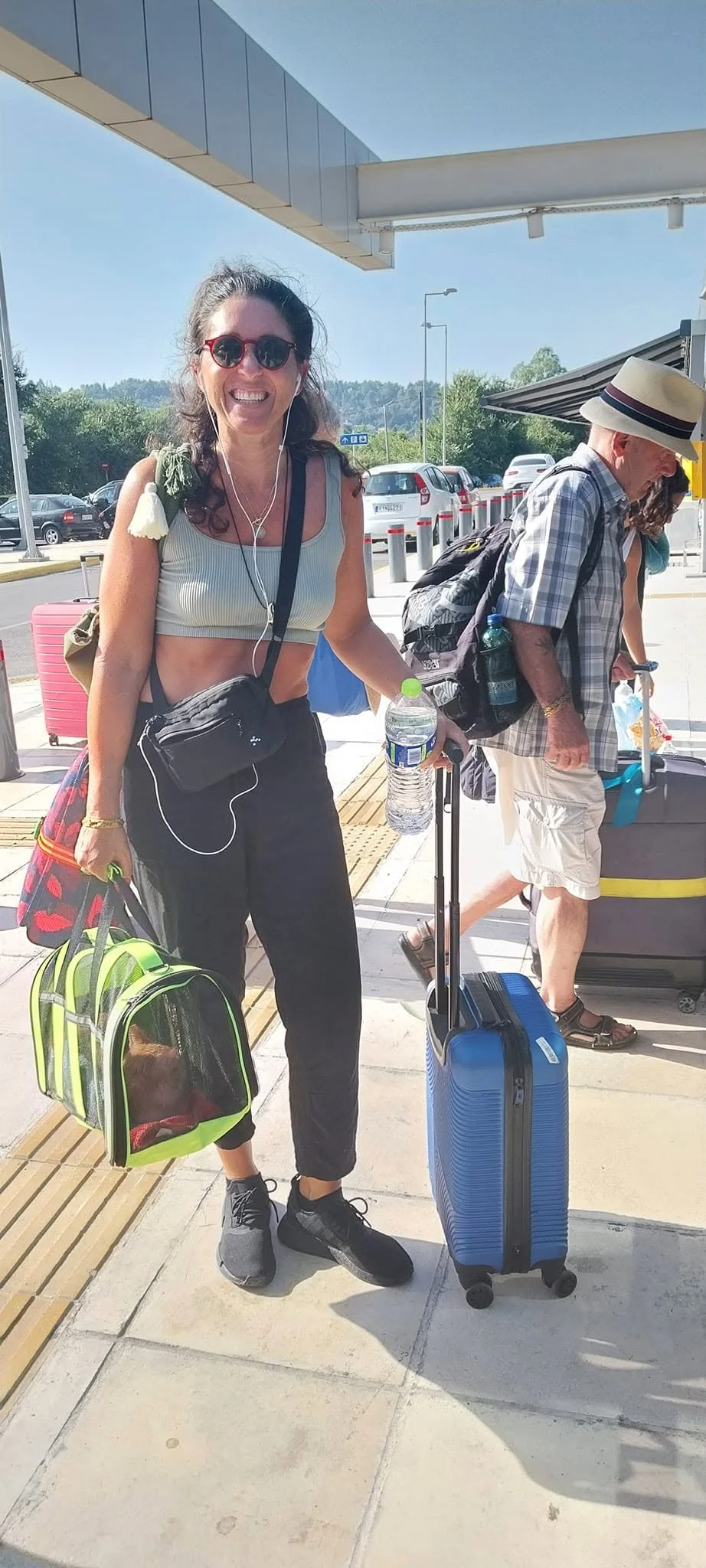A smiling Flight Patner with a cat carrier and suitcase, ready to travel