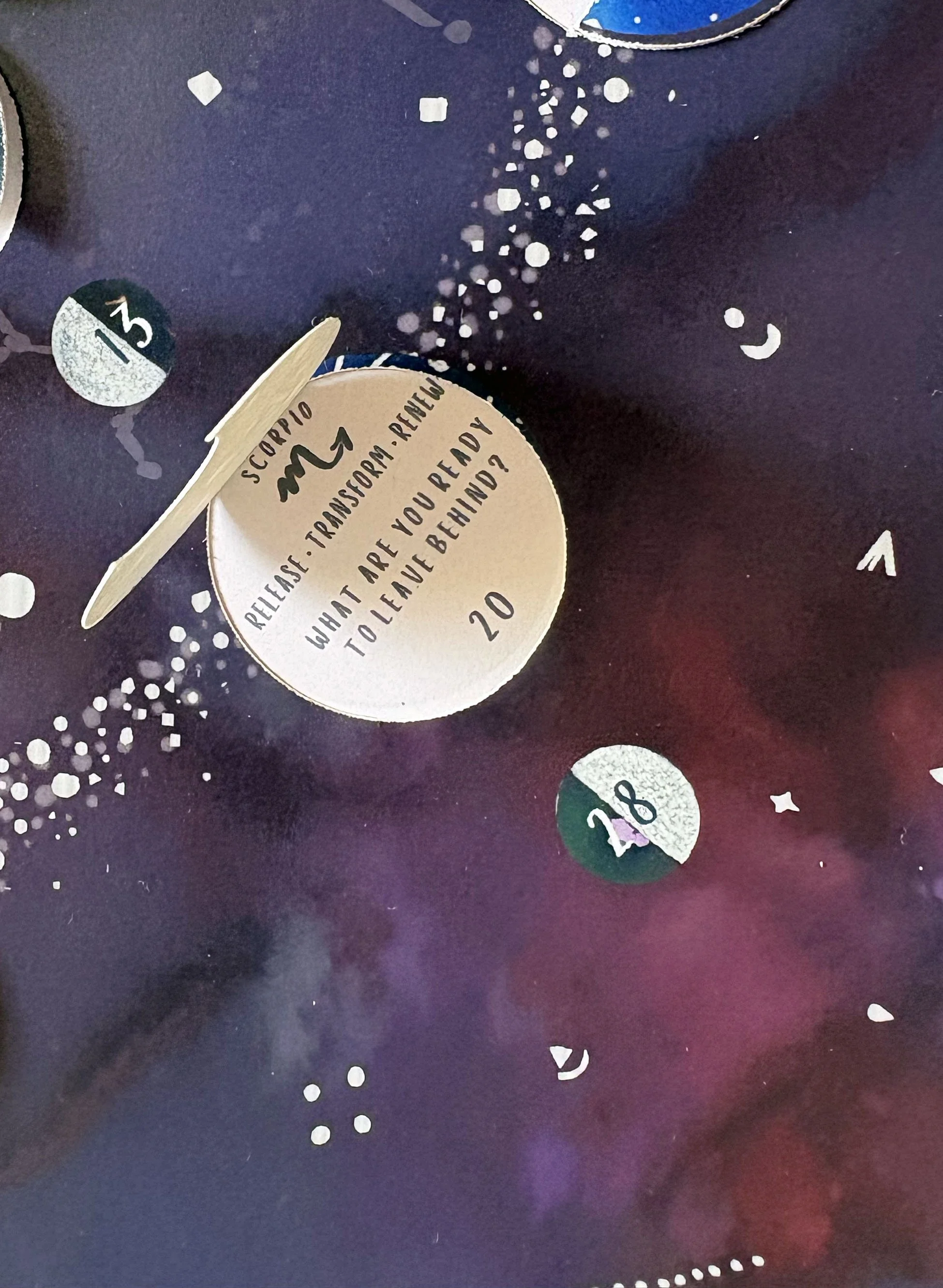 Close-up of a liftable flap on the 2027 Moon Calendar, revealing the Moon's zodiac sign, symbol, three keywords and a reflection prompt.