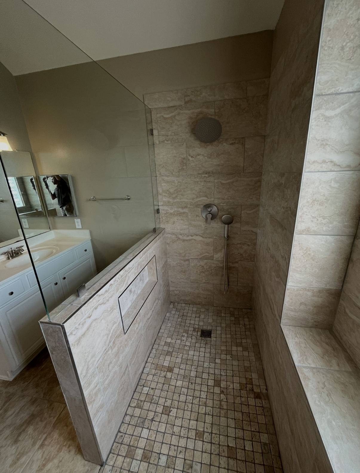 Walk-in shower with a wide entrance, glass partition, tiled flooring, and built-in wall niche, illustrating bathroom mobility and accessibility considerations before remodeling.  Copy alt text