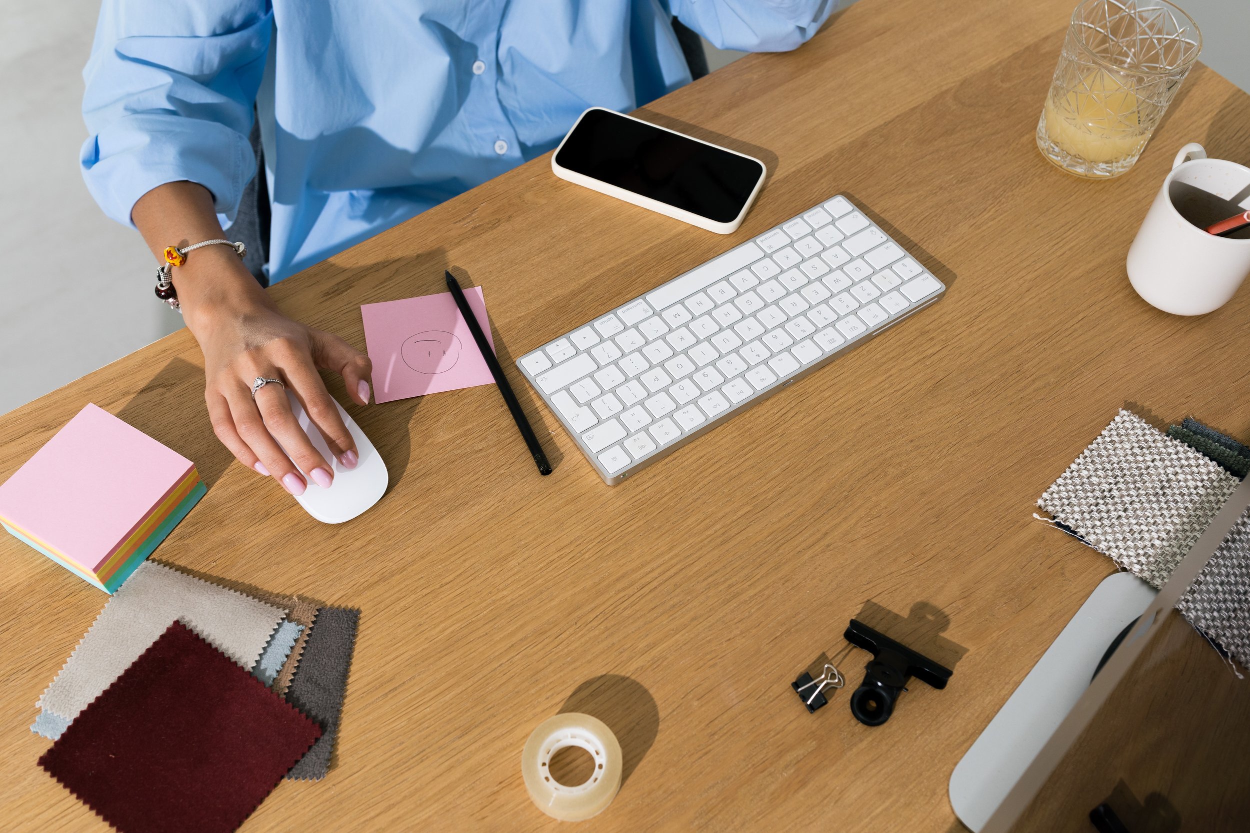 Woman sitting at a desk with a keyboard and fabric samples for an interior design business studio