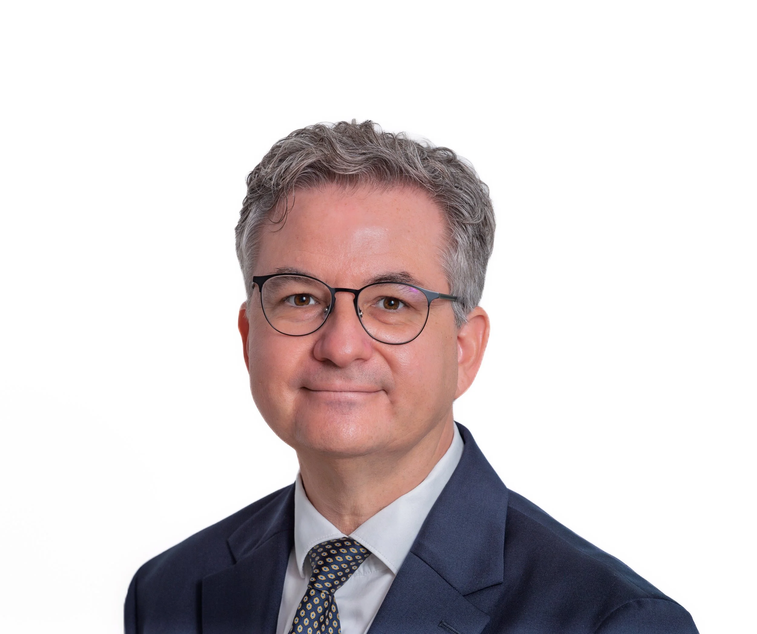 Professional headshot of Dr. Bernd C. Schmid, glasses, wearing a dark suit, white shirt, and a patterned tie, against a white background.