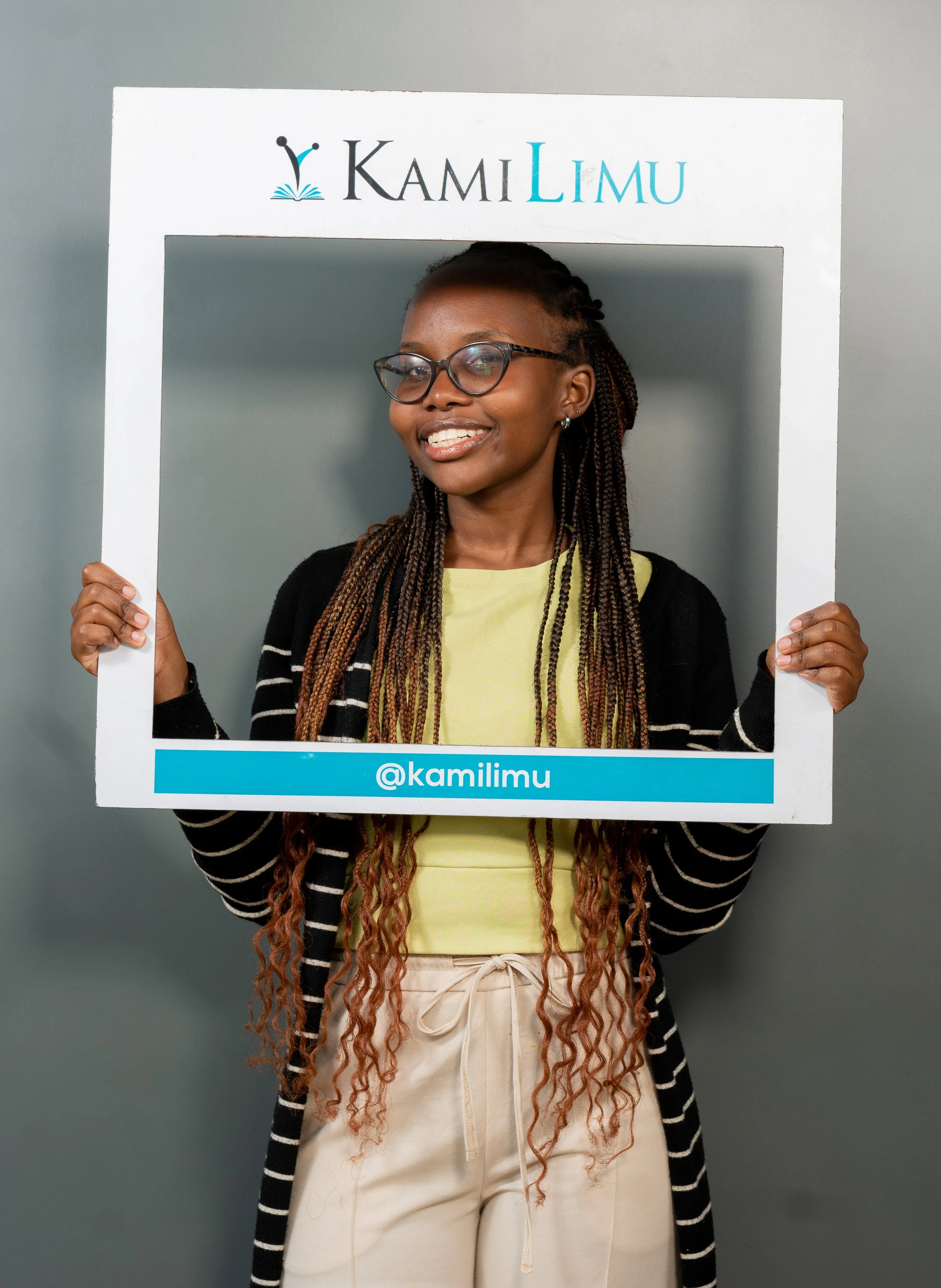 A KamiLimu Mentee called Faith Holding a KamiLimu sign smiling