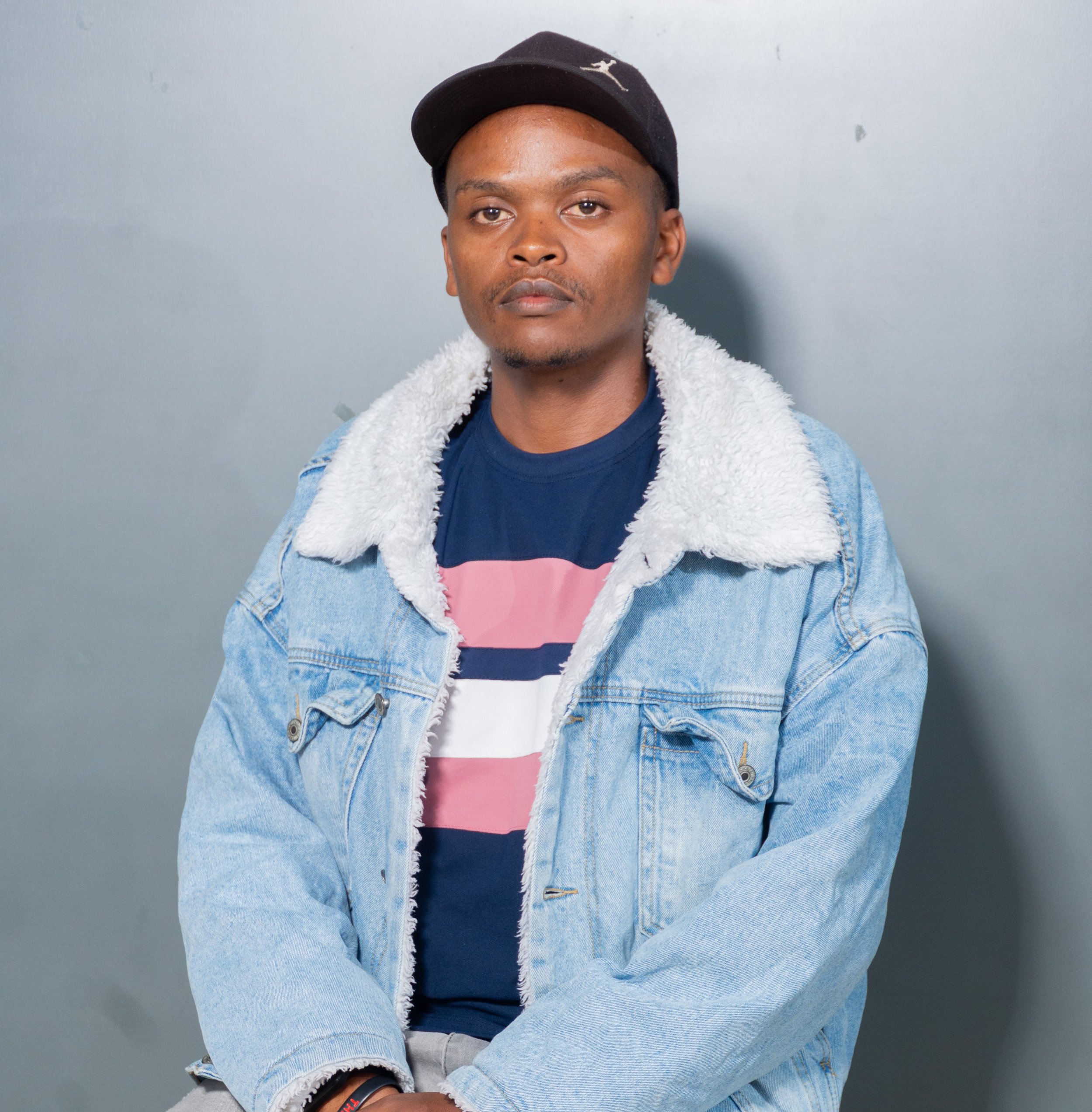 Bildad Gitonga A Kenyan Student and KamiLimu Mentee Jeans Jacket Blue Shirt with Pink Strips Wearing a Hat