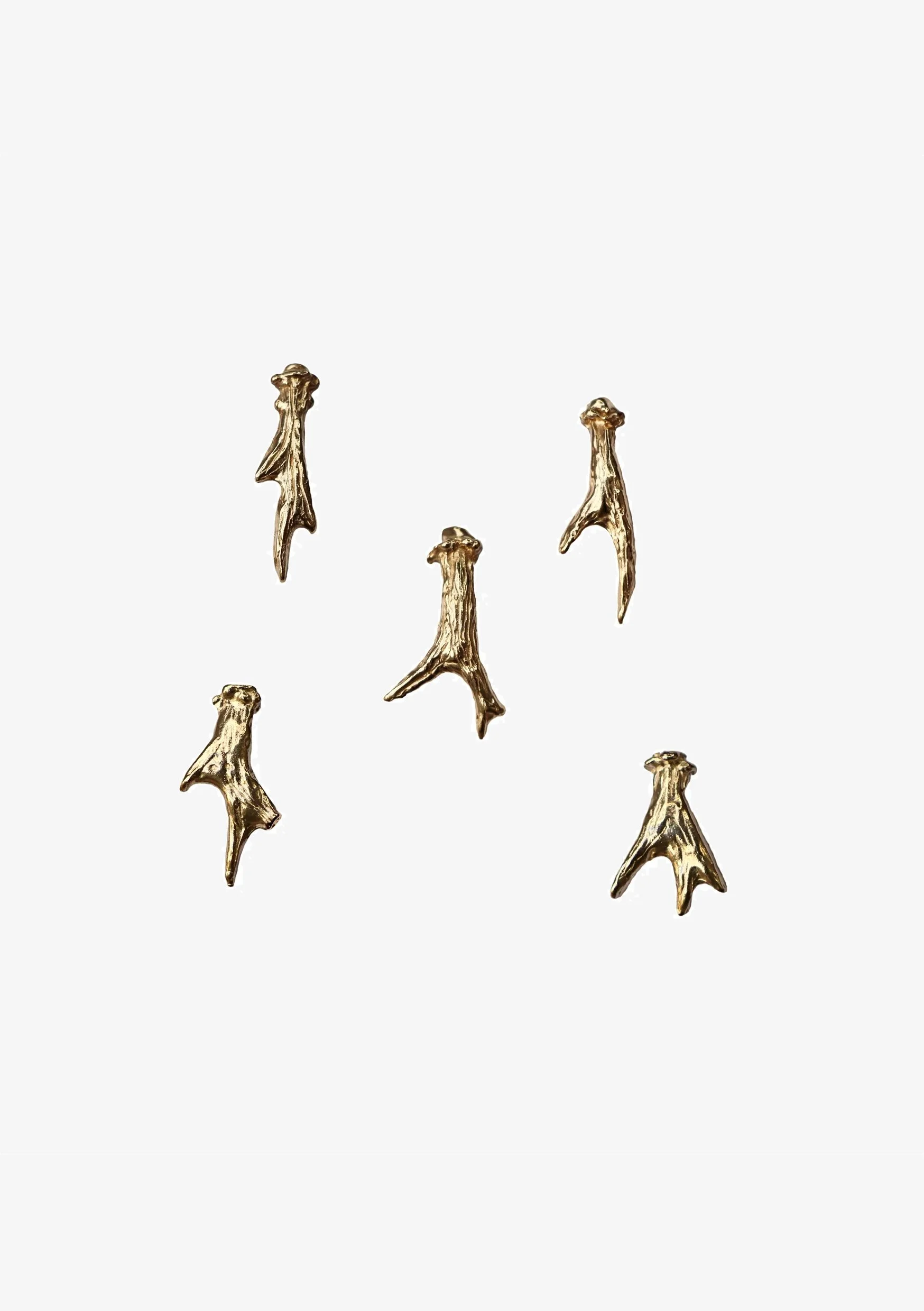 Gold-colored decorative shark fin-shaped clips arranged on a white background.