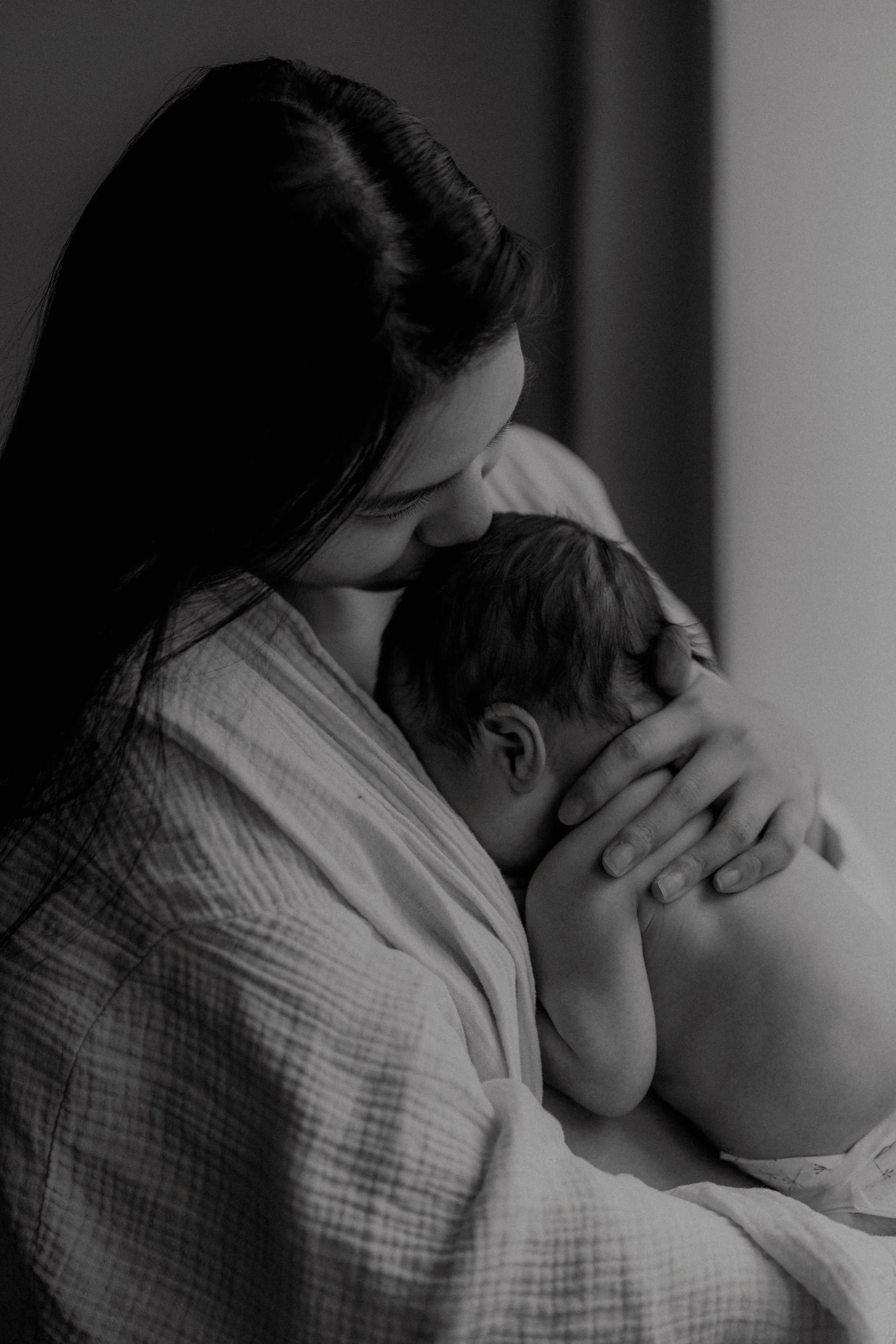 A woman holding and comforting a baby, in a tender moment, in black and white.