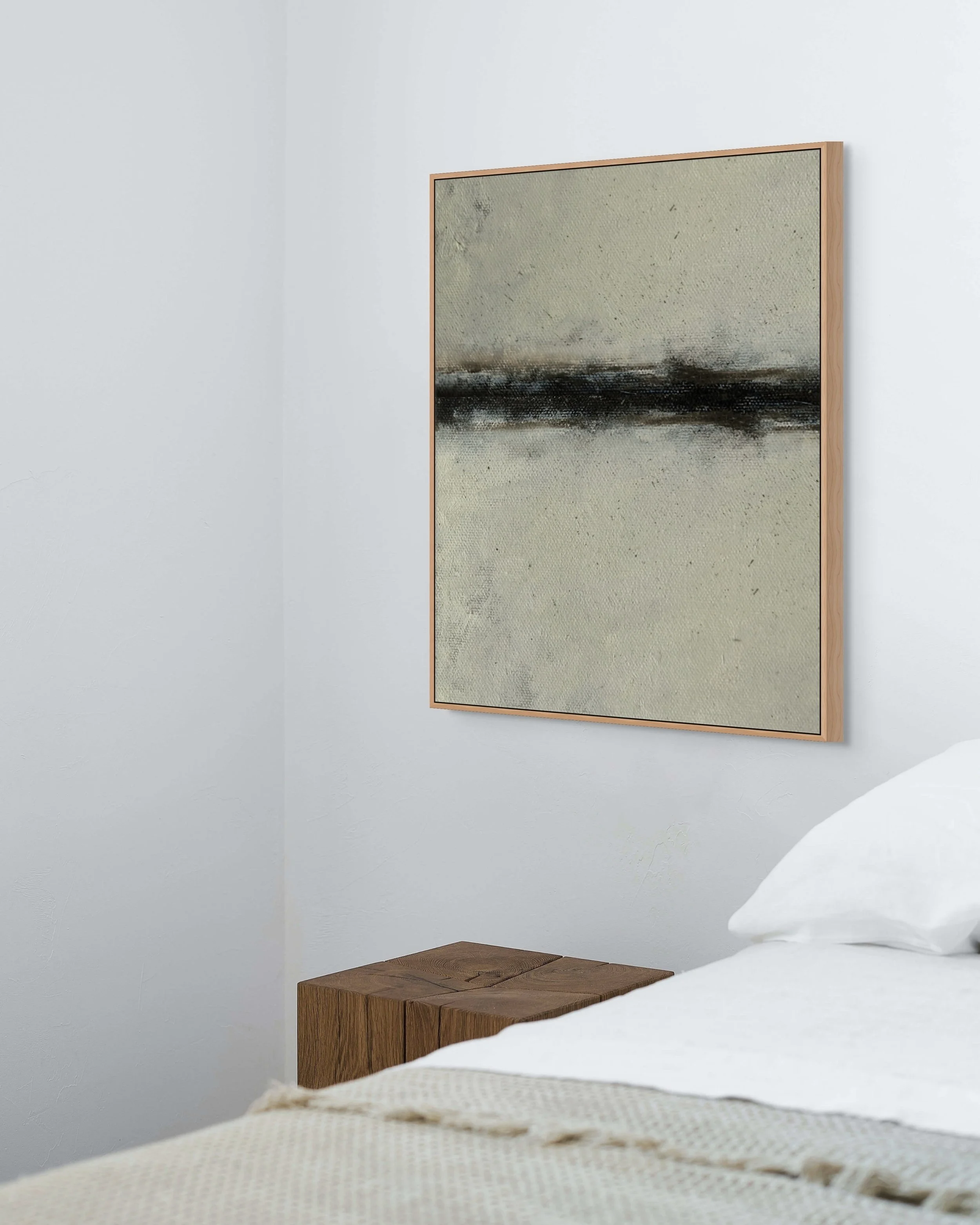 A minimalist bedroom with white walls, a wooden side table, and an abstract painting of a calm landscape hanging on the wall.