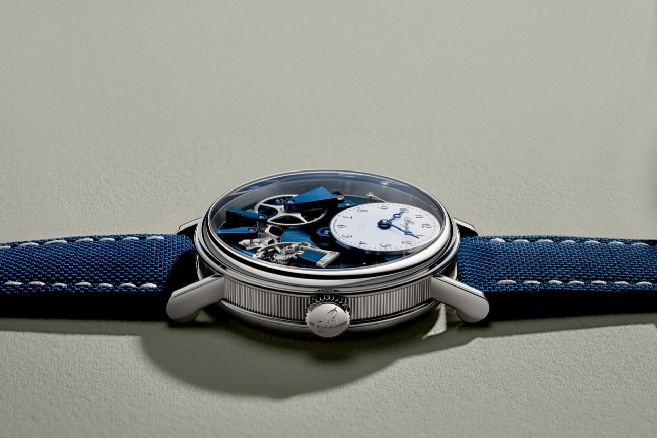Der Blick auf ein Armbanduhr mit blauer Zifferblatt und Stoffarmband auf einer hellen Oberfläche.