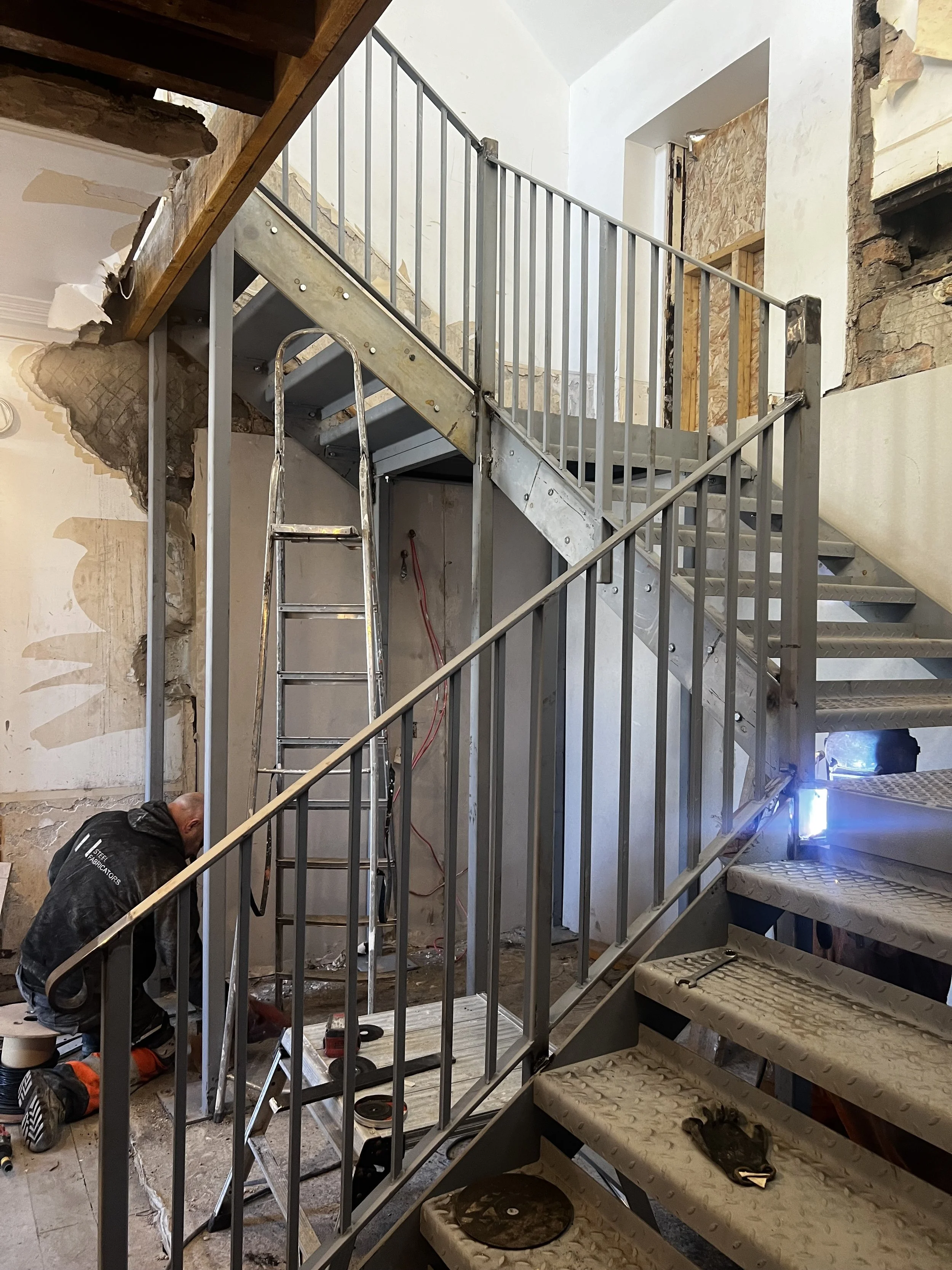 Construction workers installing staircase railing in a building under renovation.