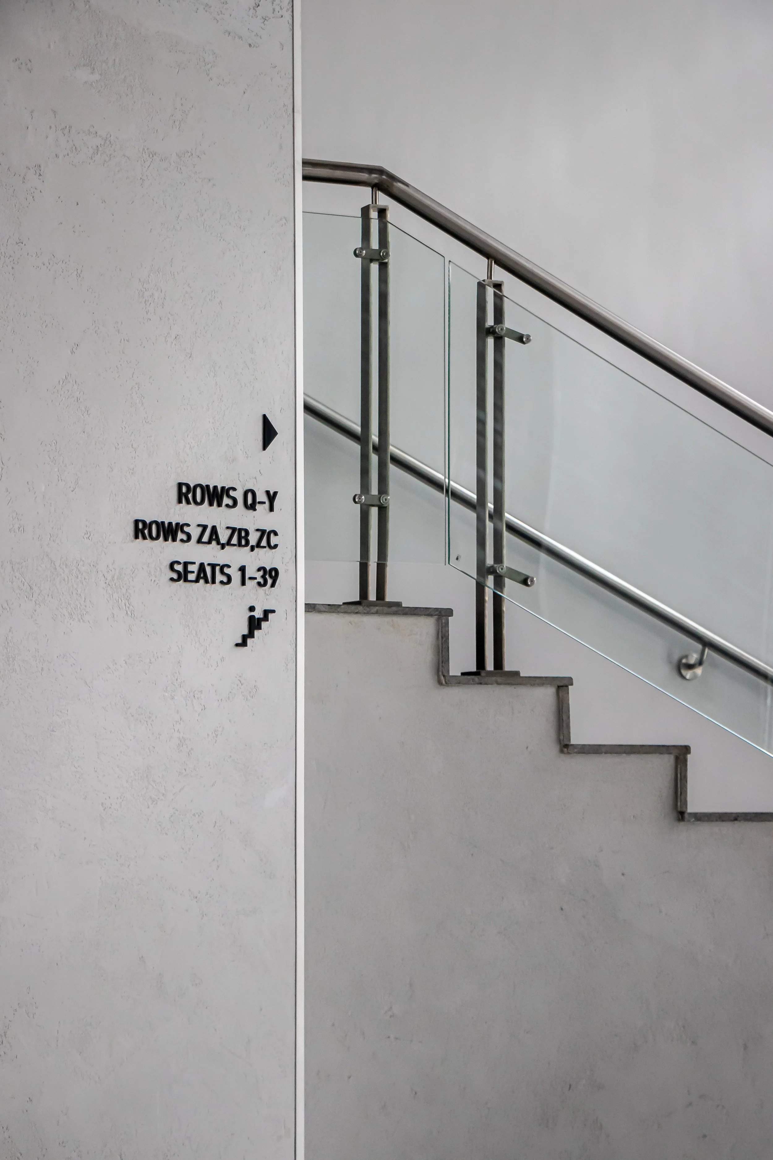 Sign indicating seating and row information next to staircase in a building.