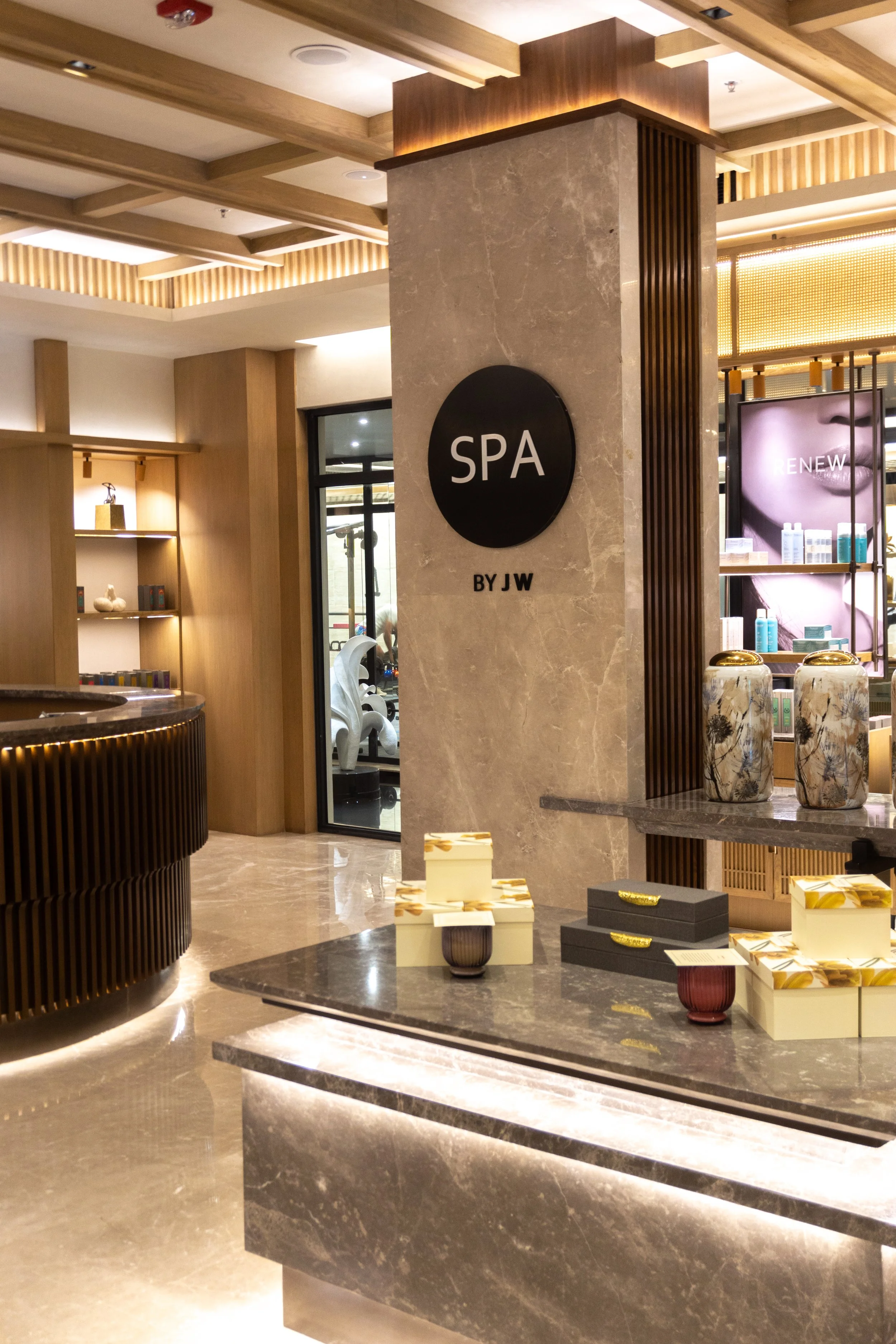 Inside a spa reception area with a sign that says 'SPA BY JW', wooden decor, and shelves with products.