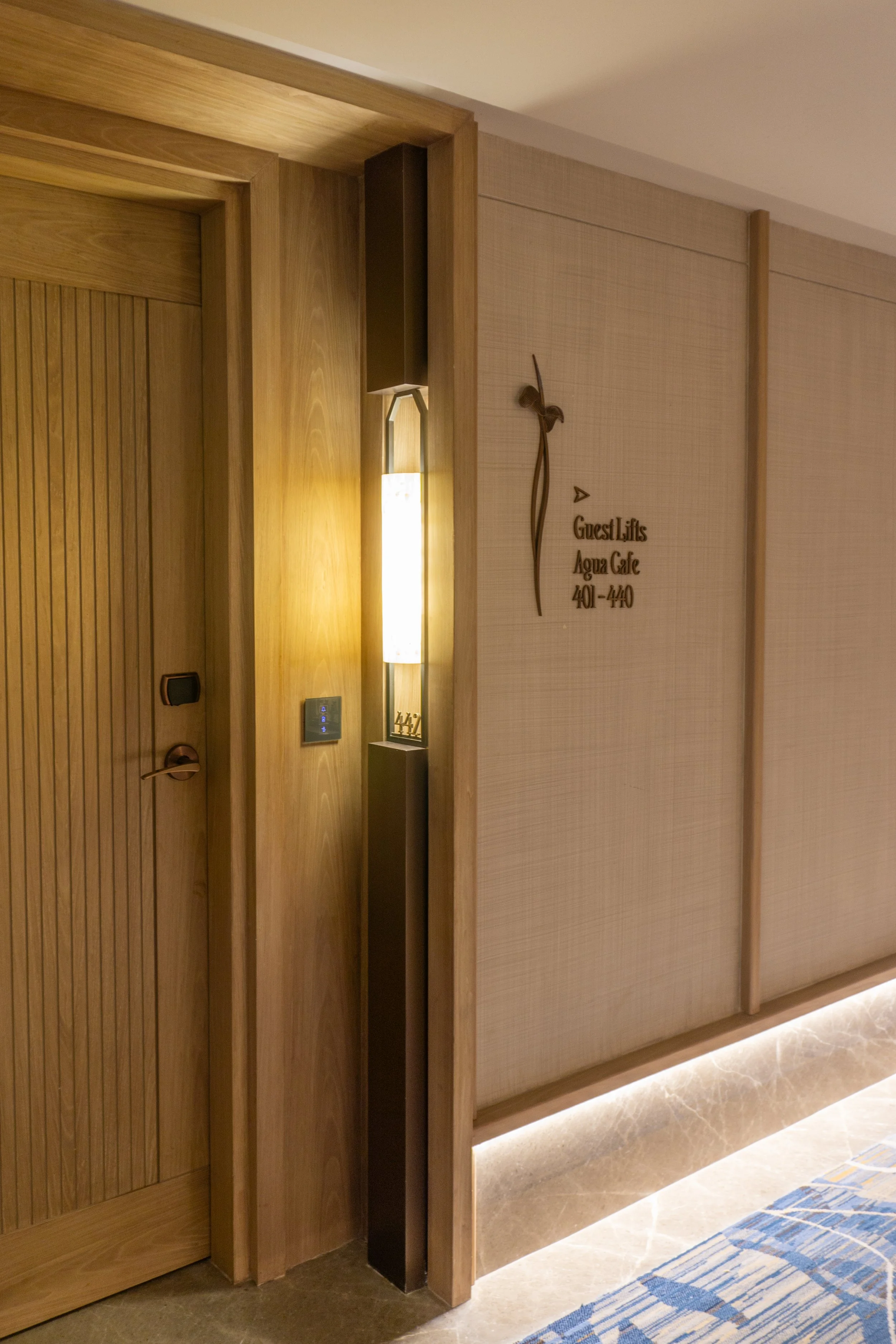 Hotel hallway wall with a sign indicating guest lifts, Aqua Cafe, and room numbers 401-440.