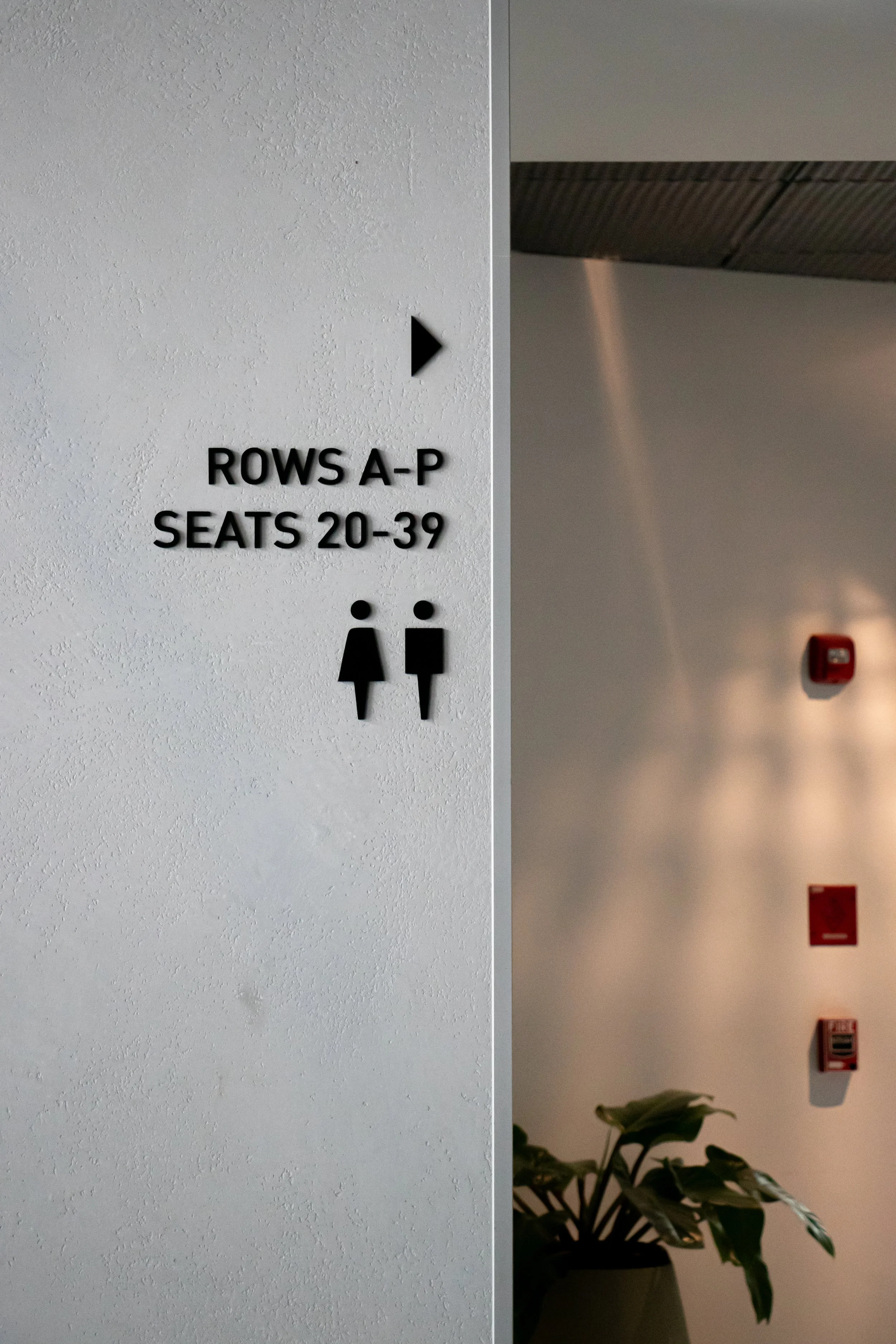 Sign indicating restroom for women and men, located in rows A-P, seats 20-39, in a public building.