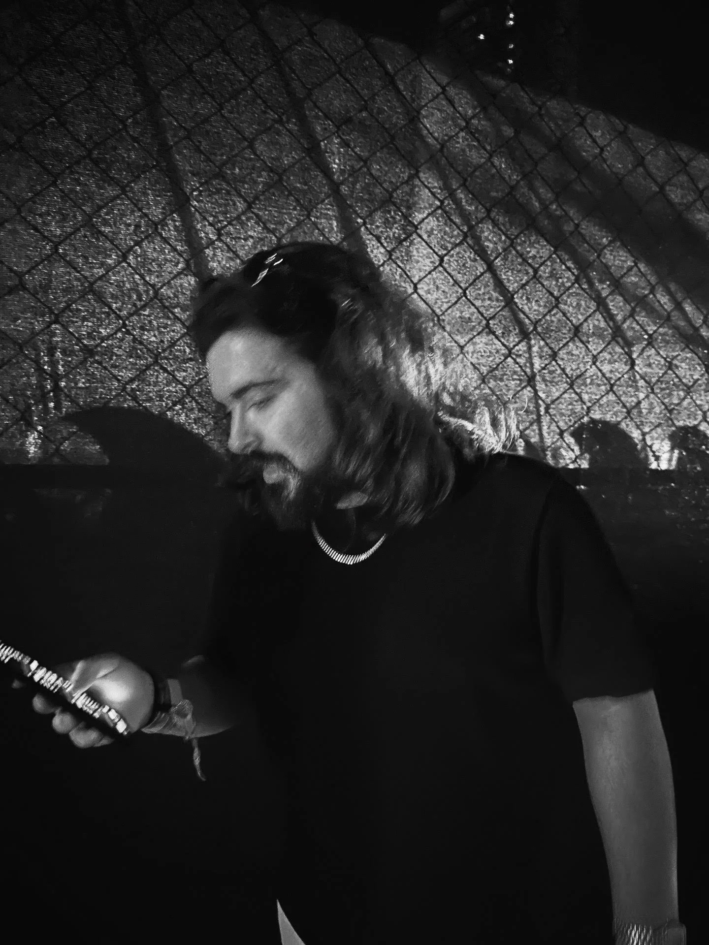 a black and white image of Mykroh, as he is backlit with a silhouette of a fence in the background