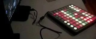 A blurry, old image of a Novation Launchpad on a grey desk.