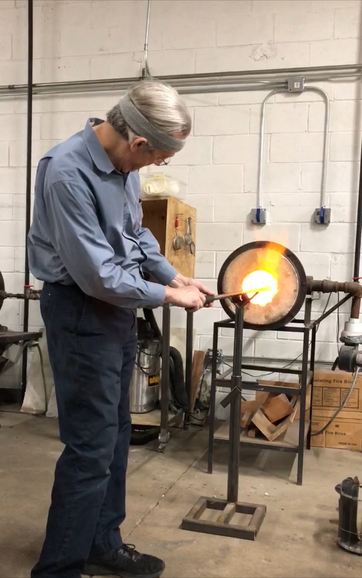 Mort Silverman, pictured working with hot glass in a glassblowing studio