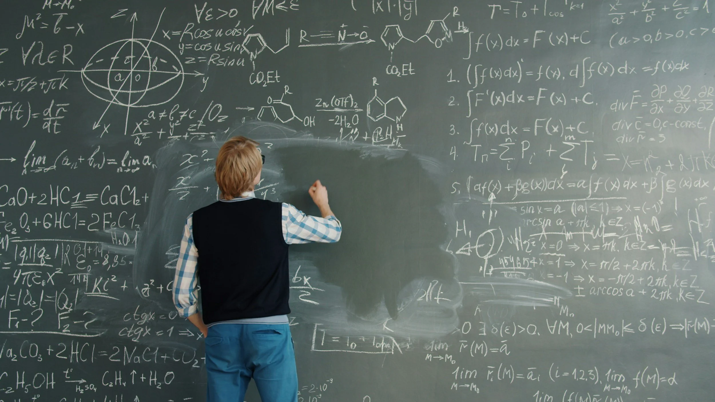 Student writing precalculus equations and functions on a chalkboard