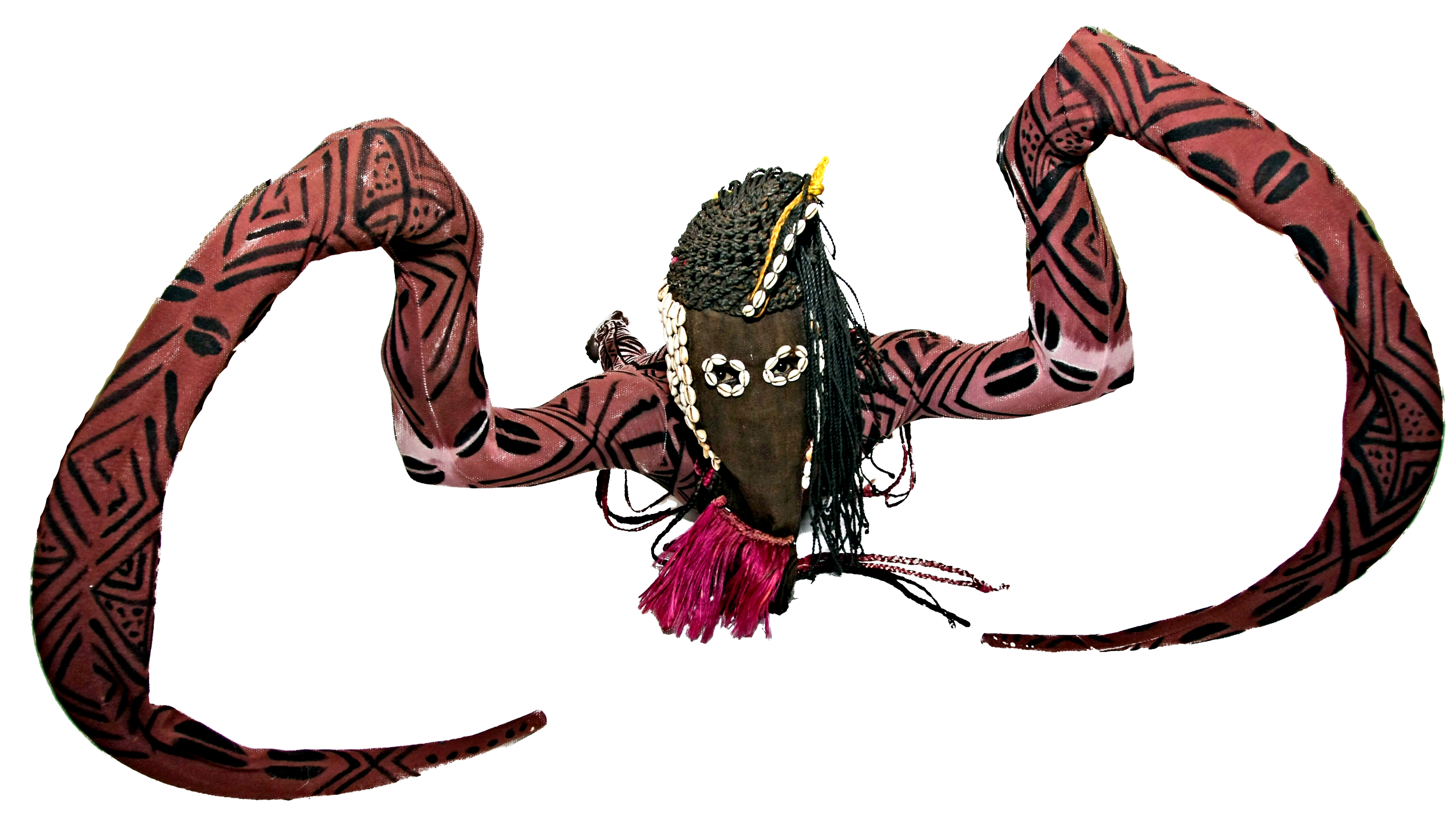 A person with dark braids adorned with shells, wearing jewelry, and a pink and black tribal patterned long-sleeve top, is posing with arms bent and head tilted forward.