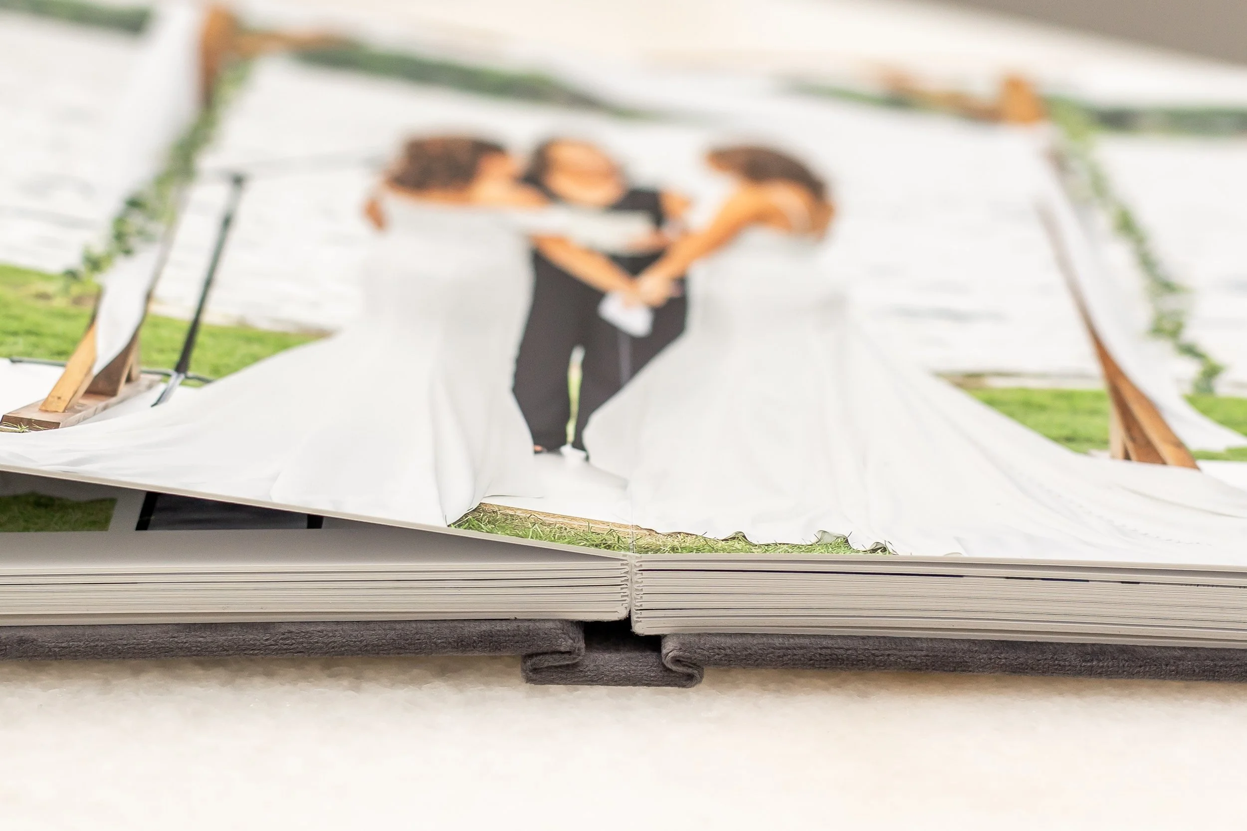 A close-up of an open photo album featuring a blurred image of a bride and groom on a white background, with wooden and metal supports visible.