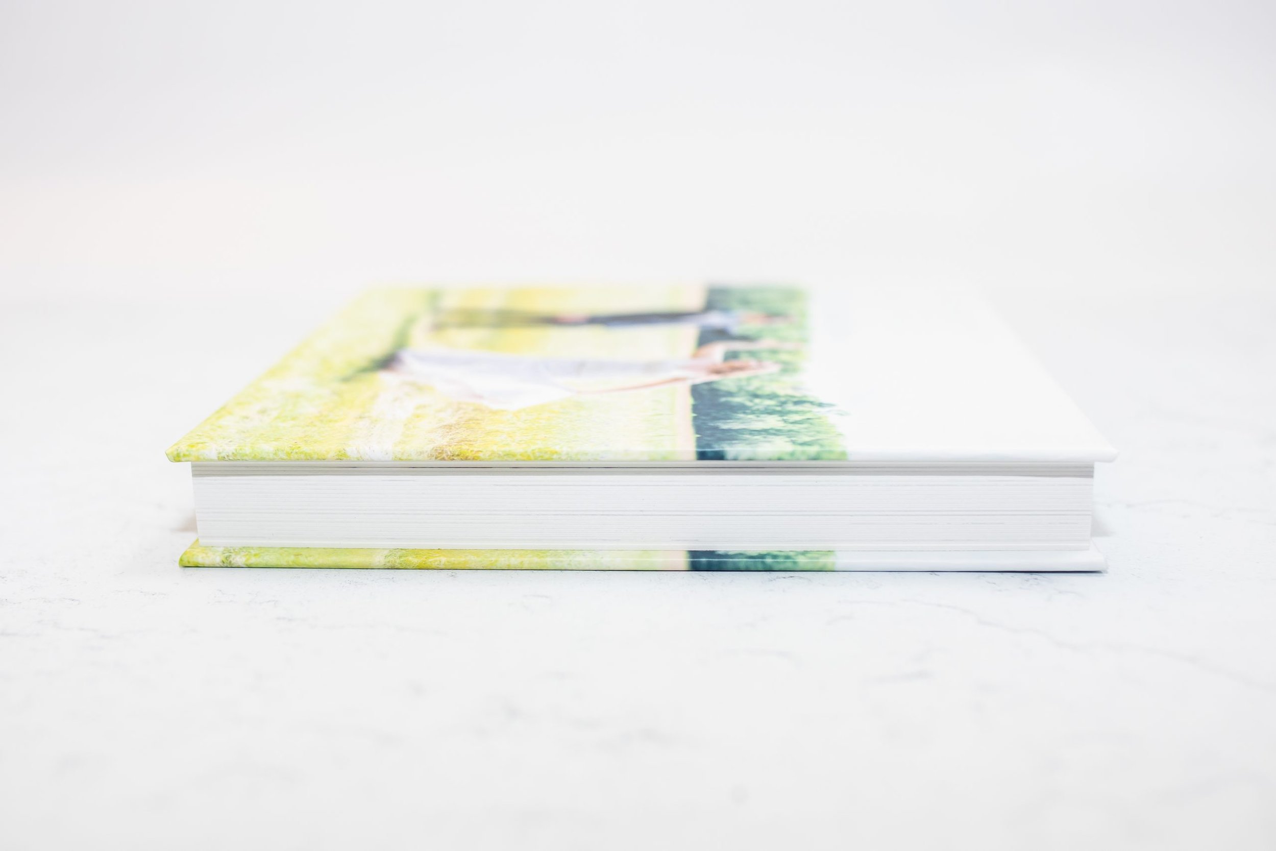 A colorful hardcover photo album with a blurred image of a person walking in a green park on the cover, placed on a white surface.