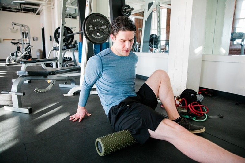Man using foam roller for leg exercise in gym