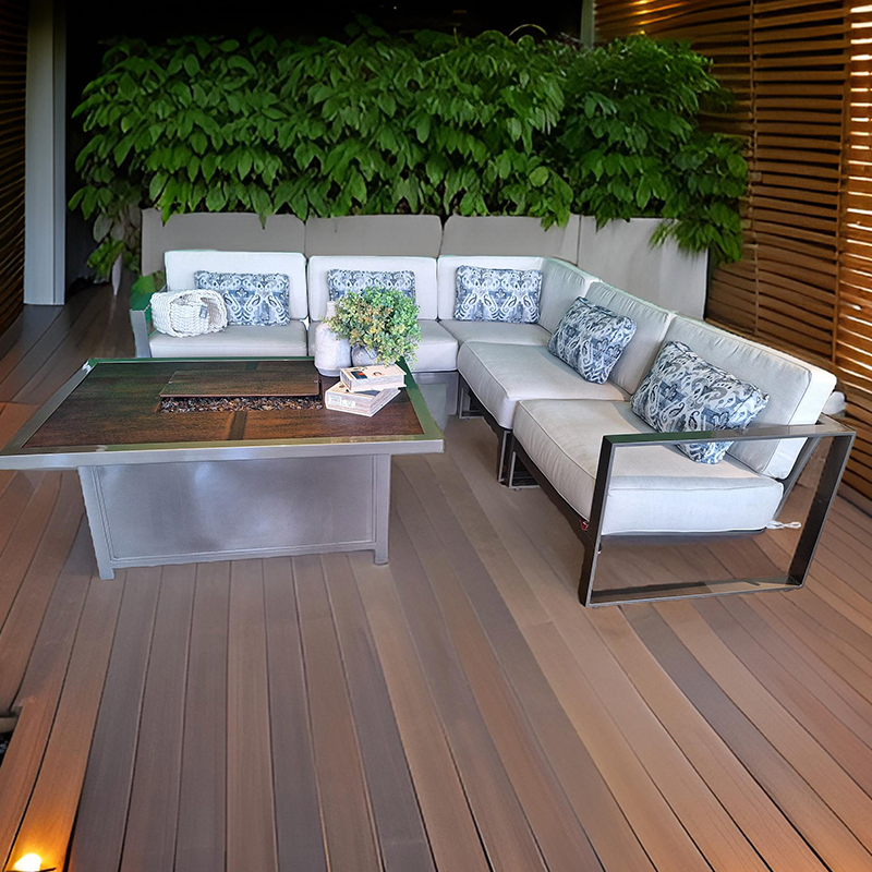 Sala de estar con sillones blancos, cojines decorativos azul y gris, una mesa de madera con una planta y libros, muro verde de plantas y paredes de madera en un ambiente moderno y elegante.