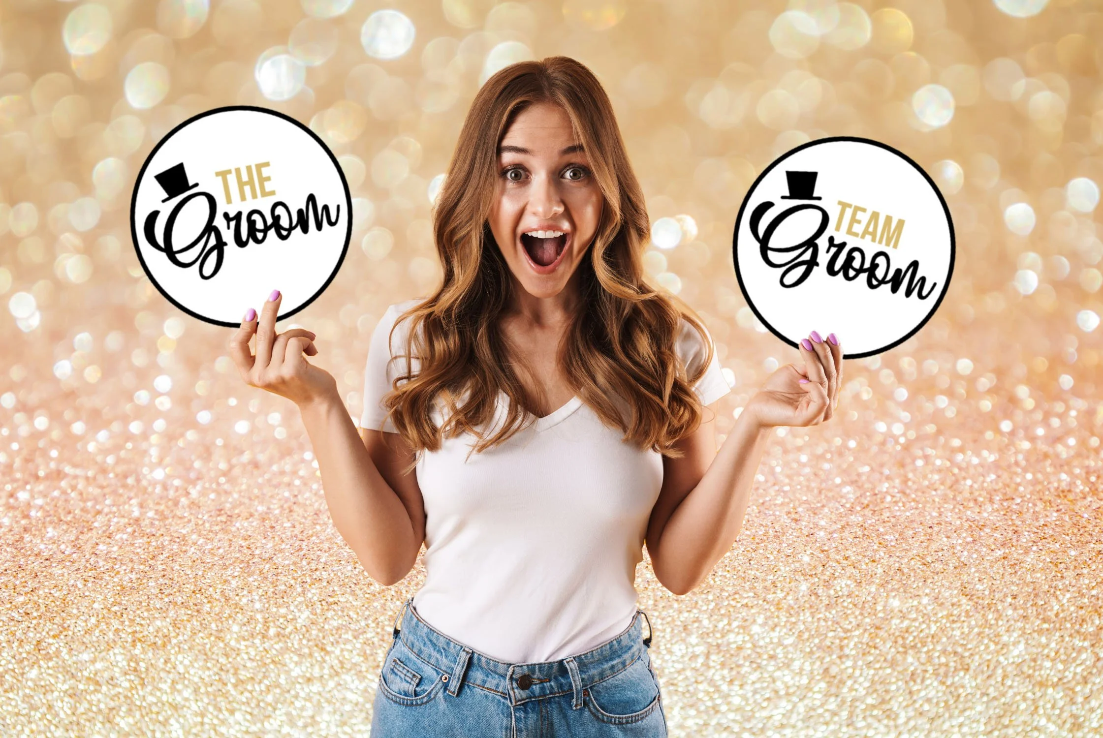 A woman with long, wavy brown hair holding two circular signs with the words 'The Groom' and 'Team Groom' against a glittery, golden background.