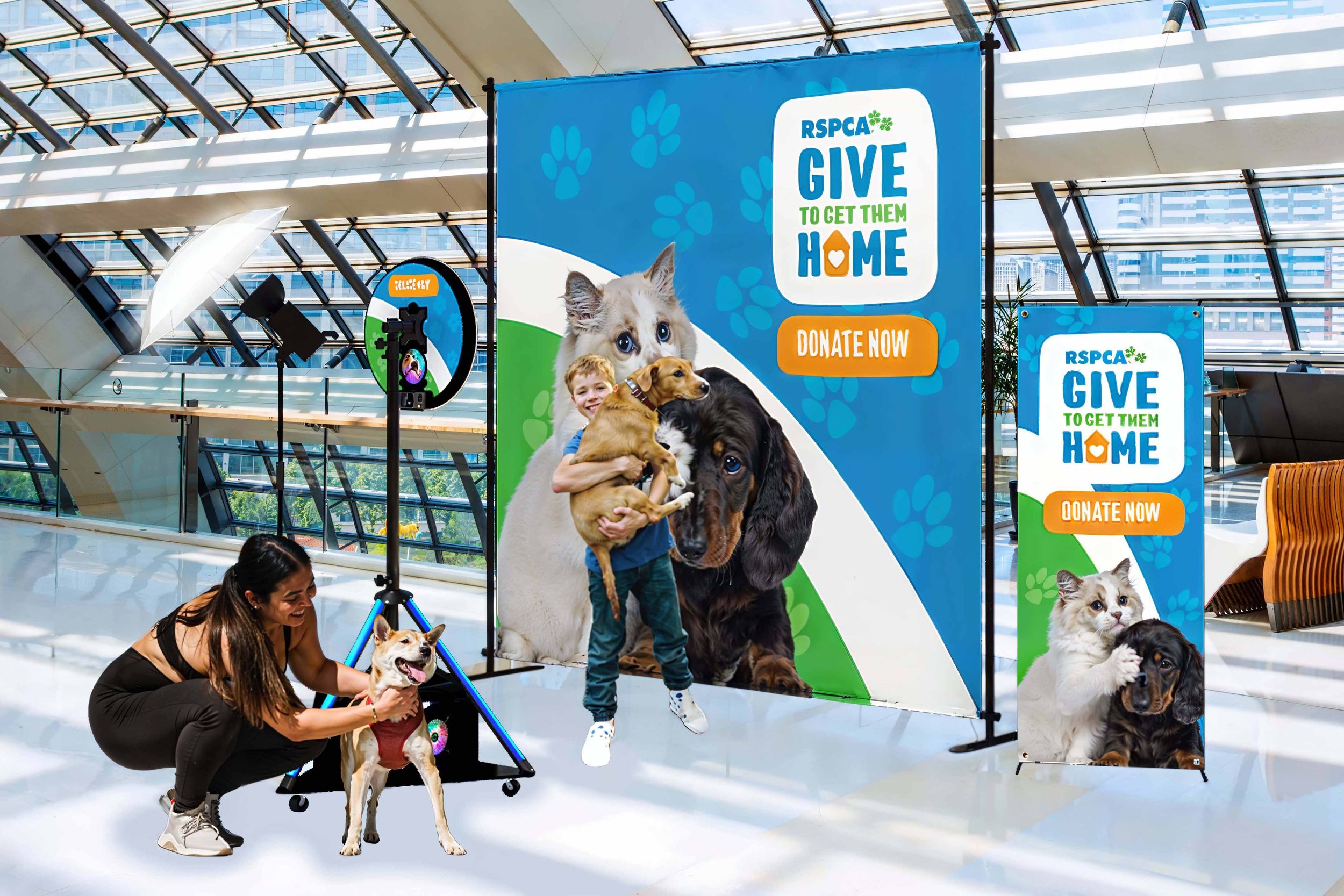 Heartwarming scene from a Darwin community event with large blue RSPCA banners, featuring a young girl holding a puppy and women with their dogs.