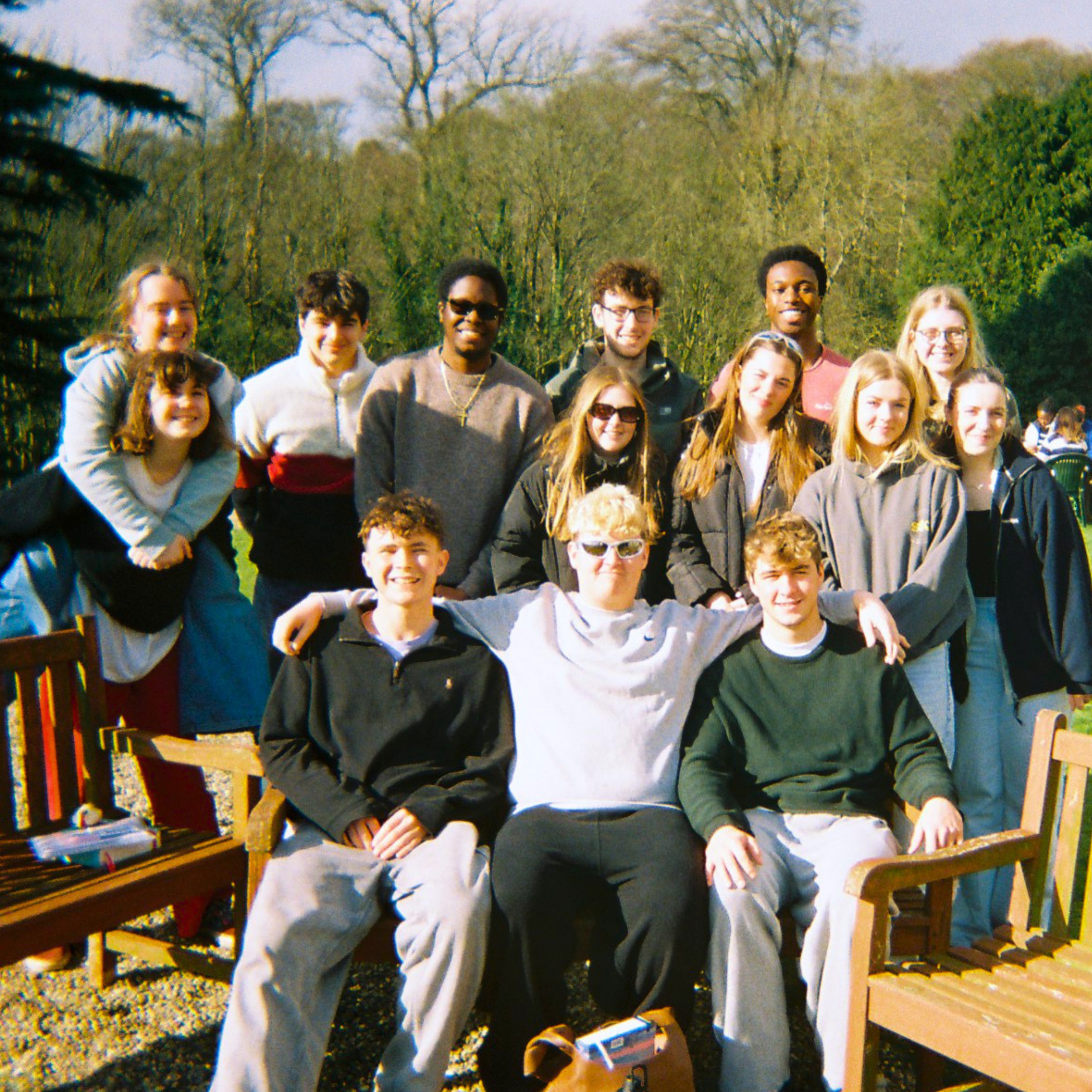 Image of young people sitting on a bench smiling and enjoying time together.