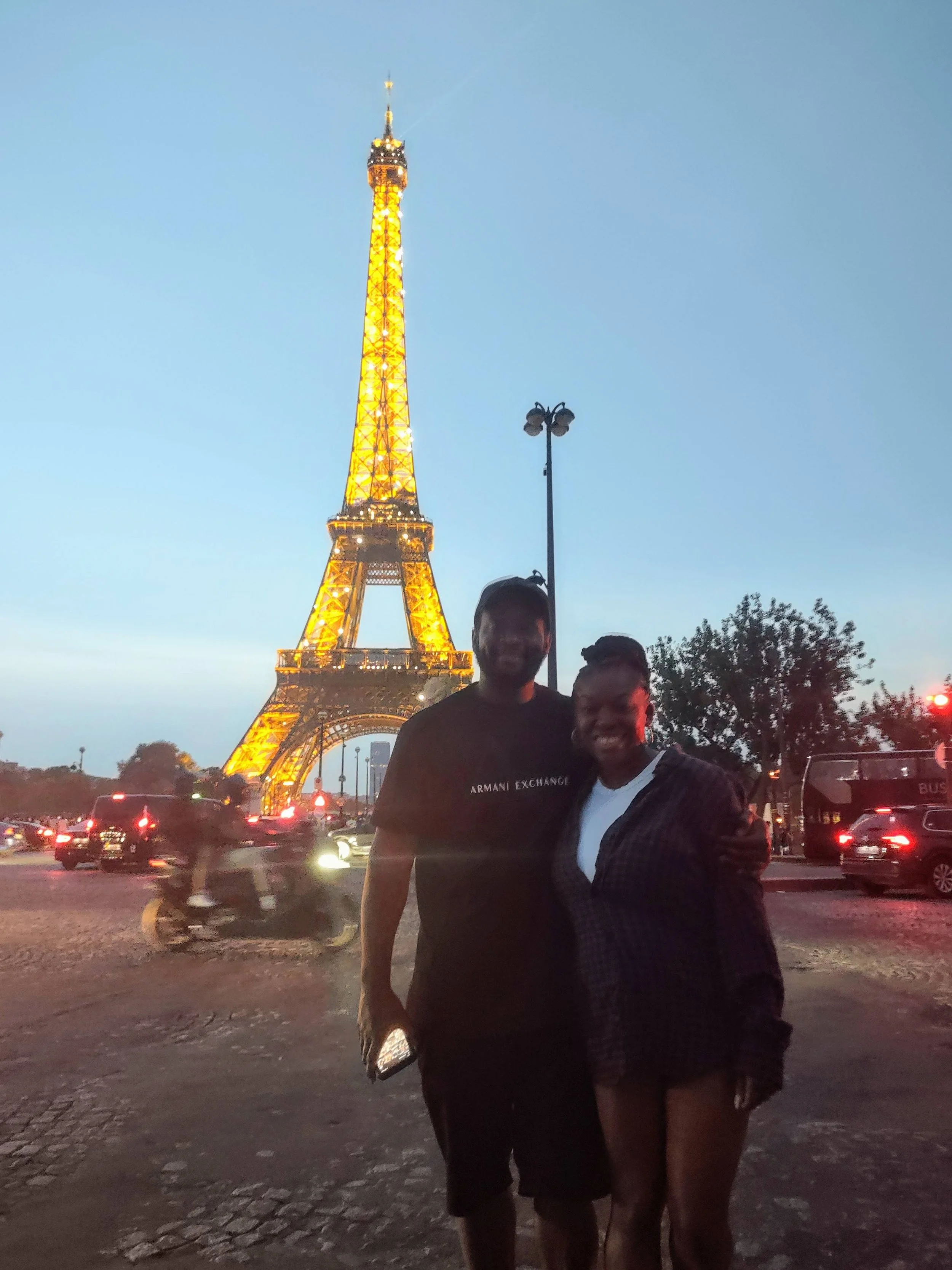 Couple standing in front of an illuminated Eiffel tower.