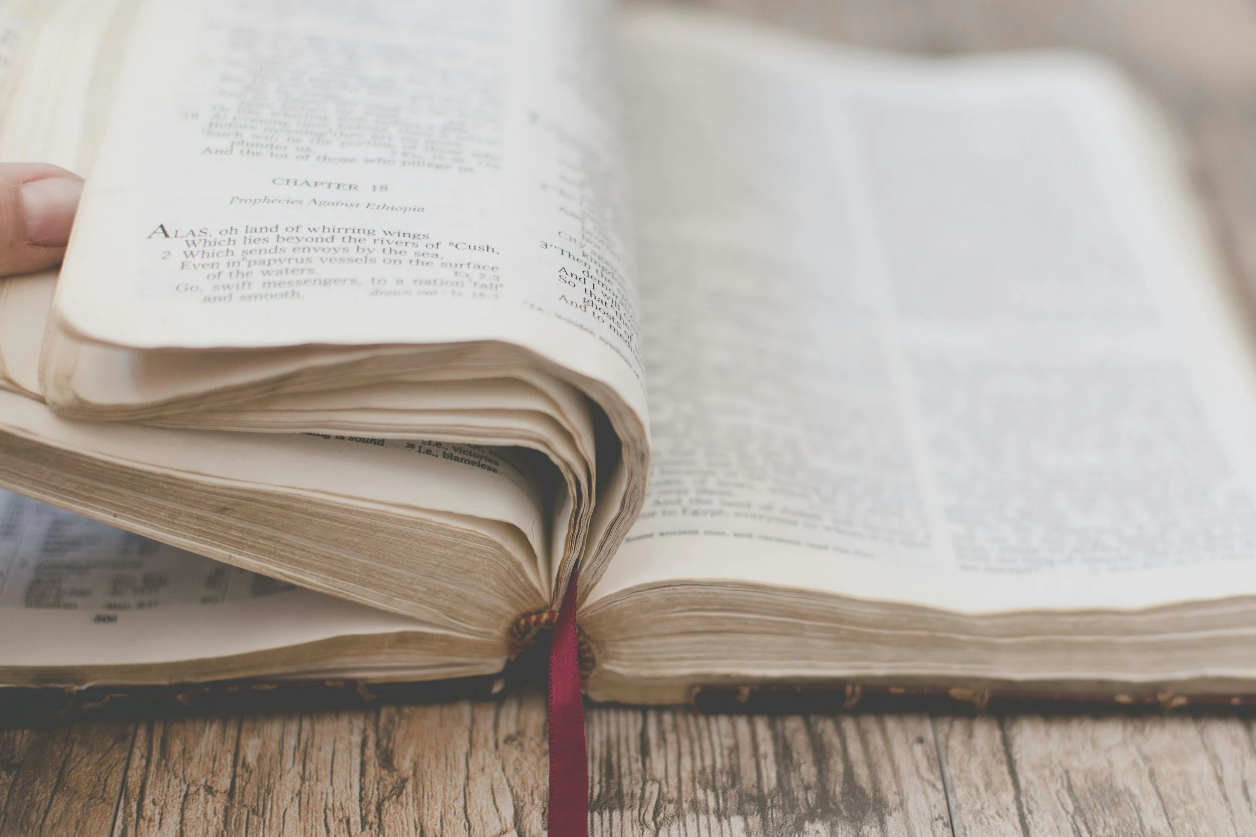 Open Bible on a wooden table, text blurred by camera lens