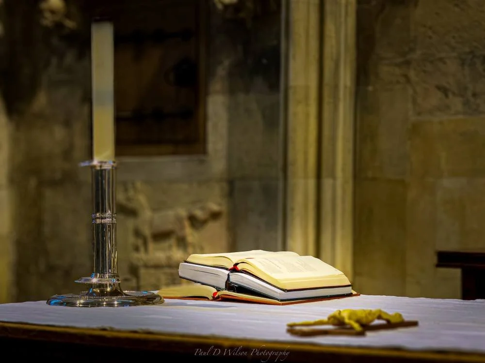 open bible next to mug, overlooking a sparkly water