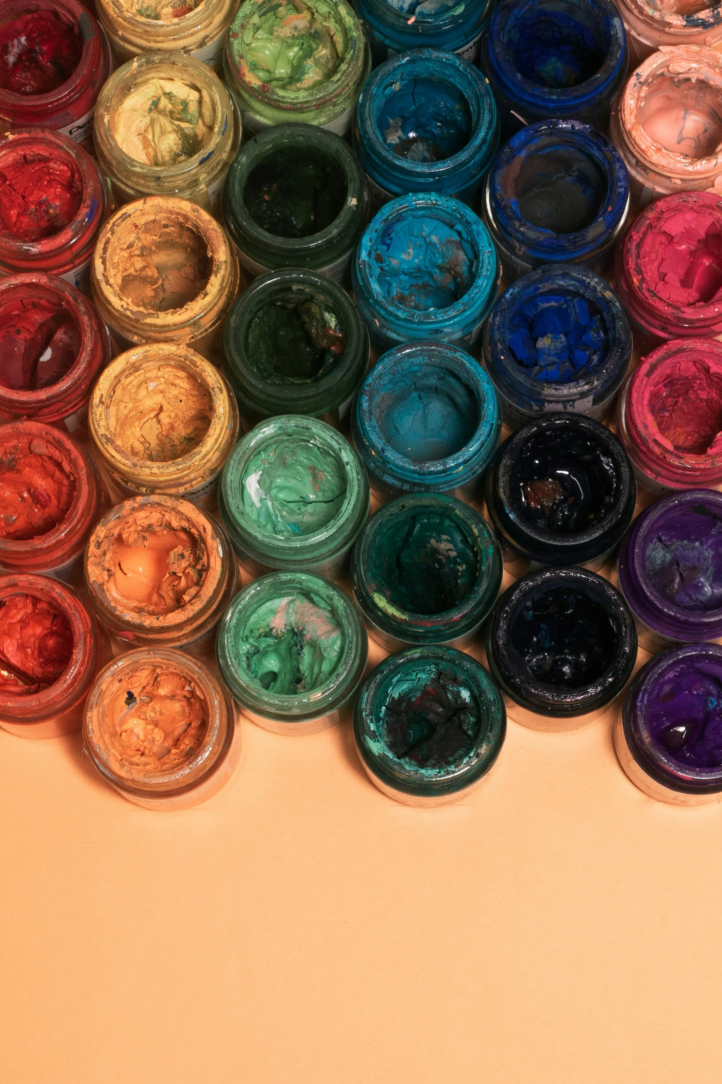 Open pots of paints in colours red, orange, green, blue and purple