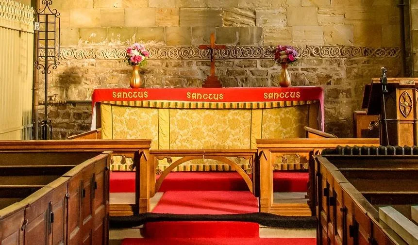 A Holy Communion table against the bare stone walls of a parish church
