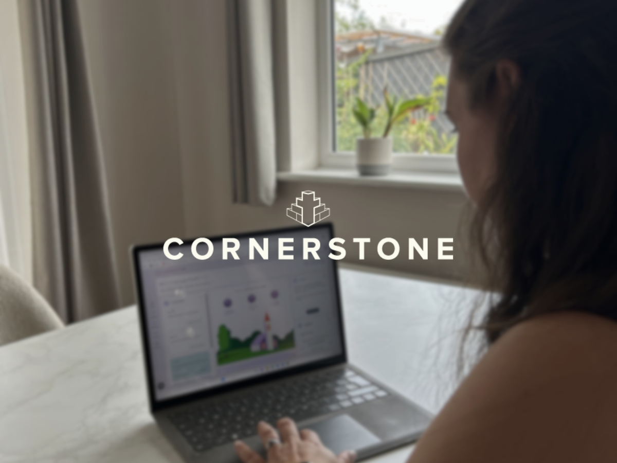 Image of lady sat at dining table, laptop open to cornerstone dashboard