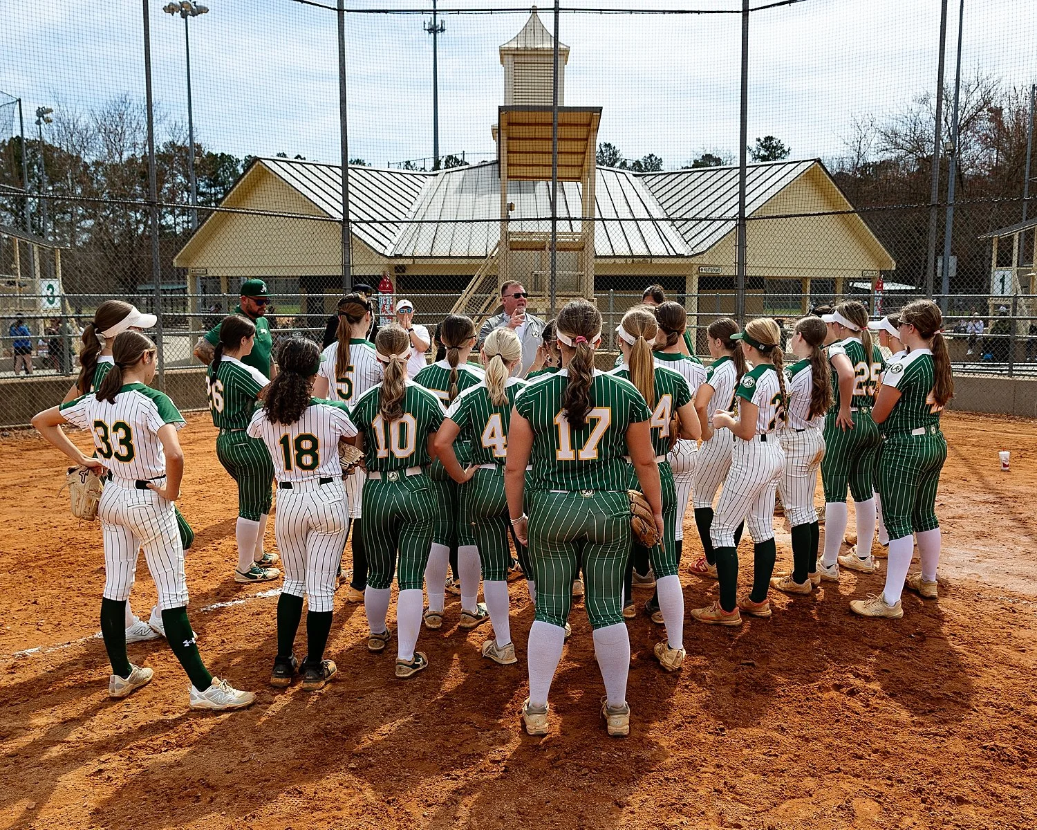  team in green uniforms stand around home plate by Tiaras Monet Photography  